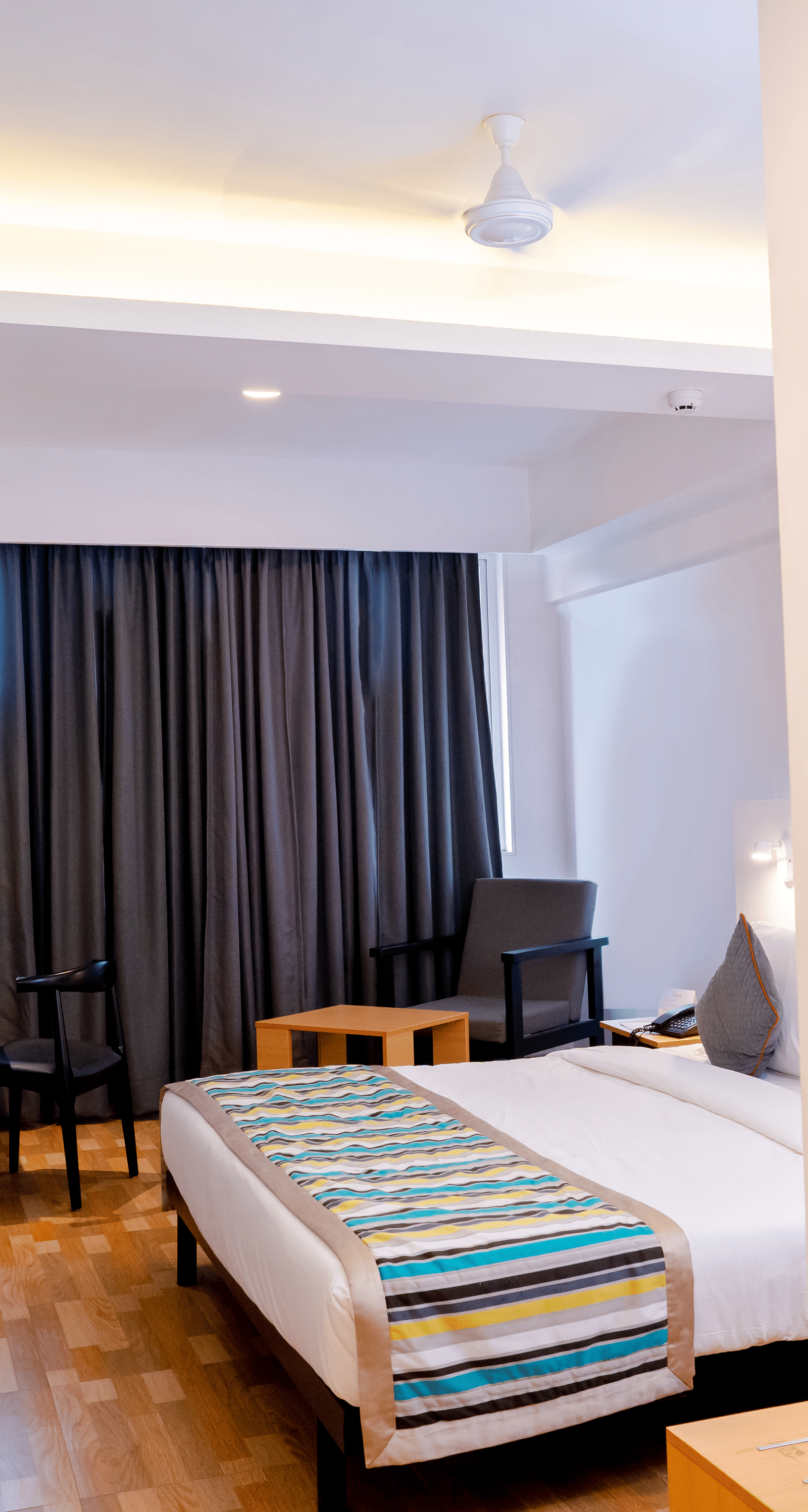 A modern hotel room with a bed, gray curtains and contemporary decor - TGI Ameya Grand, Goa