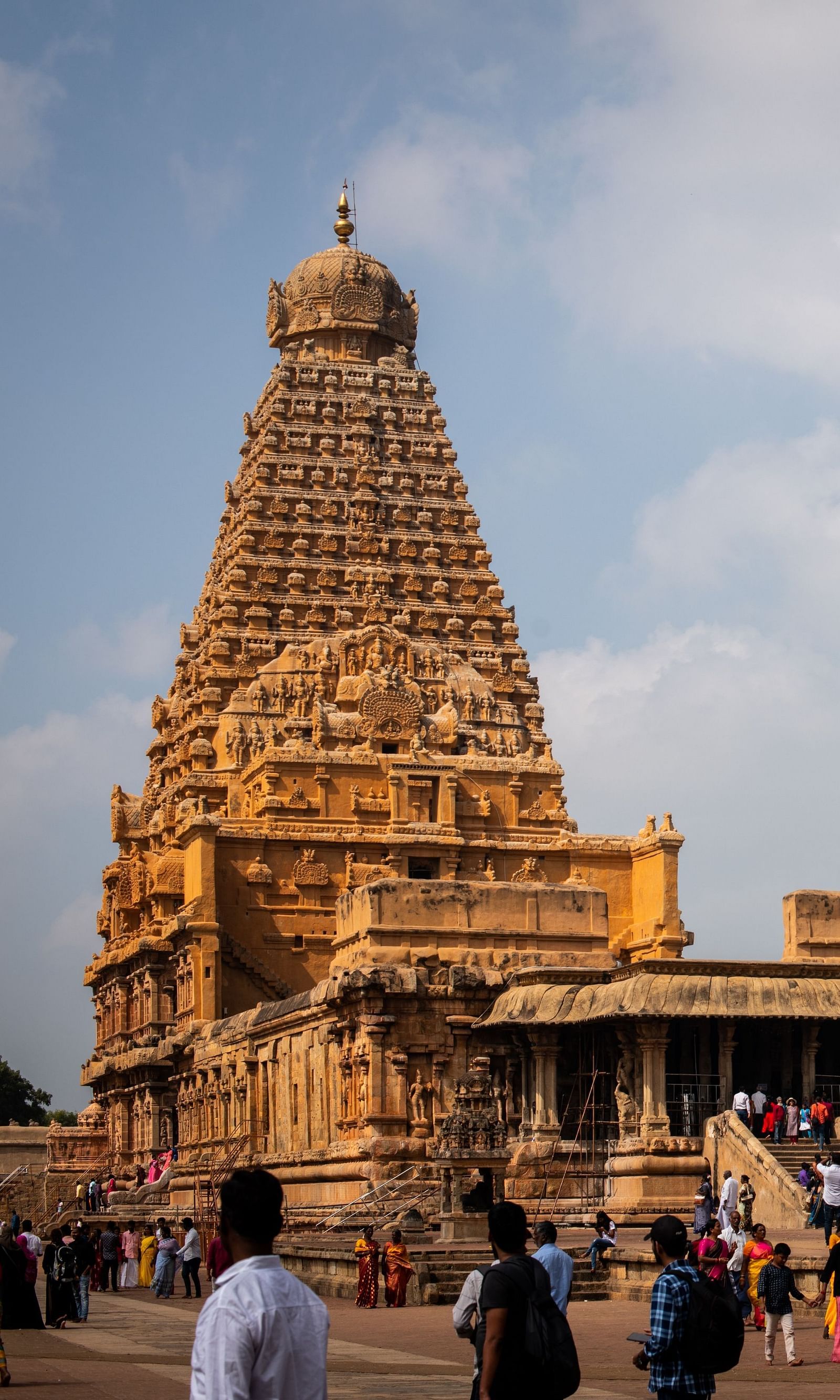 An image of a temple where many devotees are seen with the backdrop of a blue sky