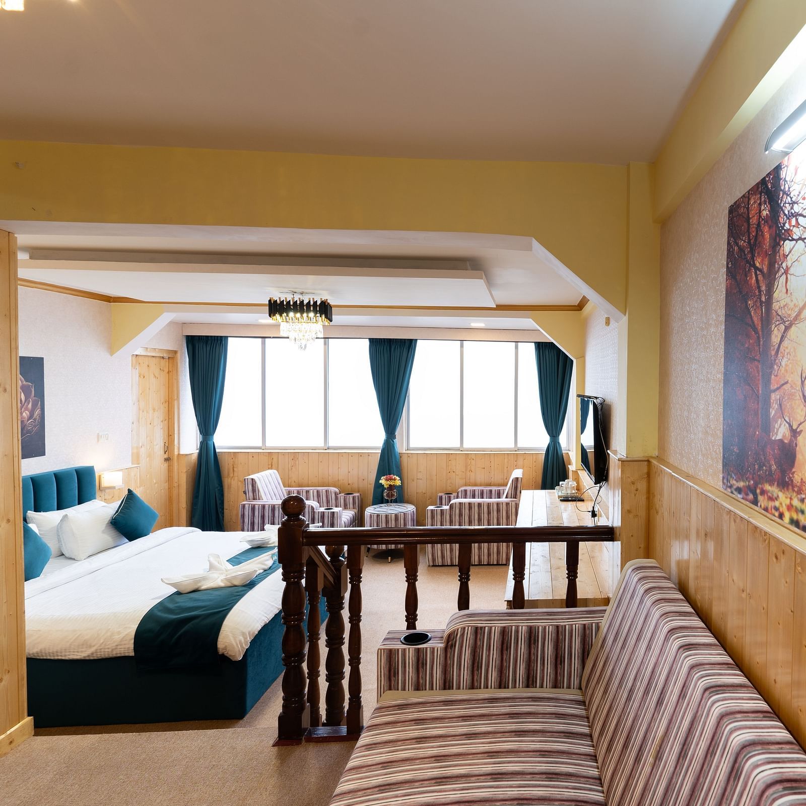 Suite with a king size bed, wall-mounted television, wooden table, and cosy lighting along with attached living room at Avianna Seven Seas, Darjeeling
