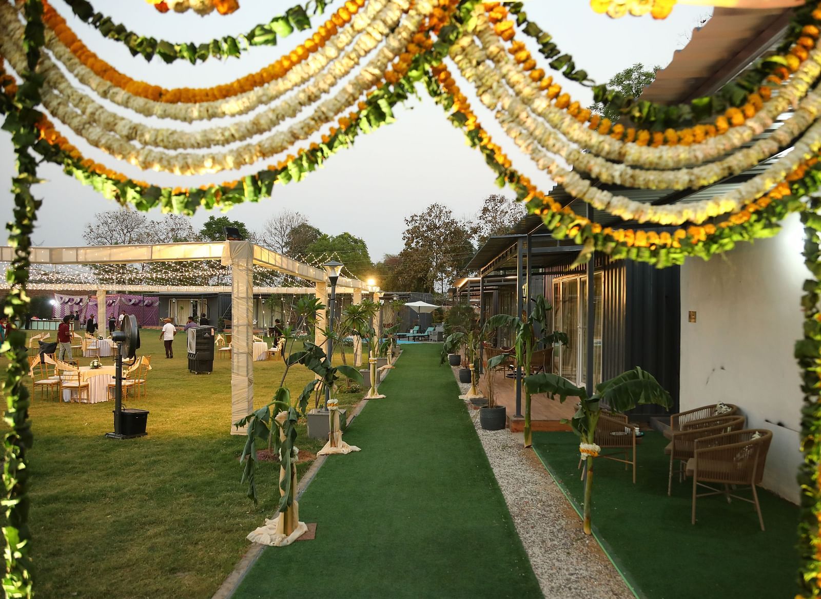 Venue entrance at Tisya Farms, Gurgaon with floral arch, green carpet, and guests walking inside.
