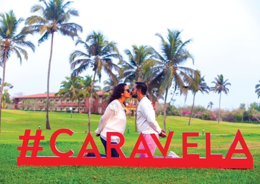 a couple kissing in front of a #Caravela sign - Caravela Beach Resort Goa