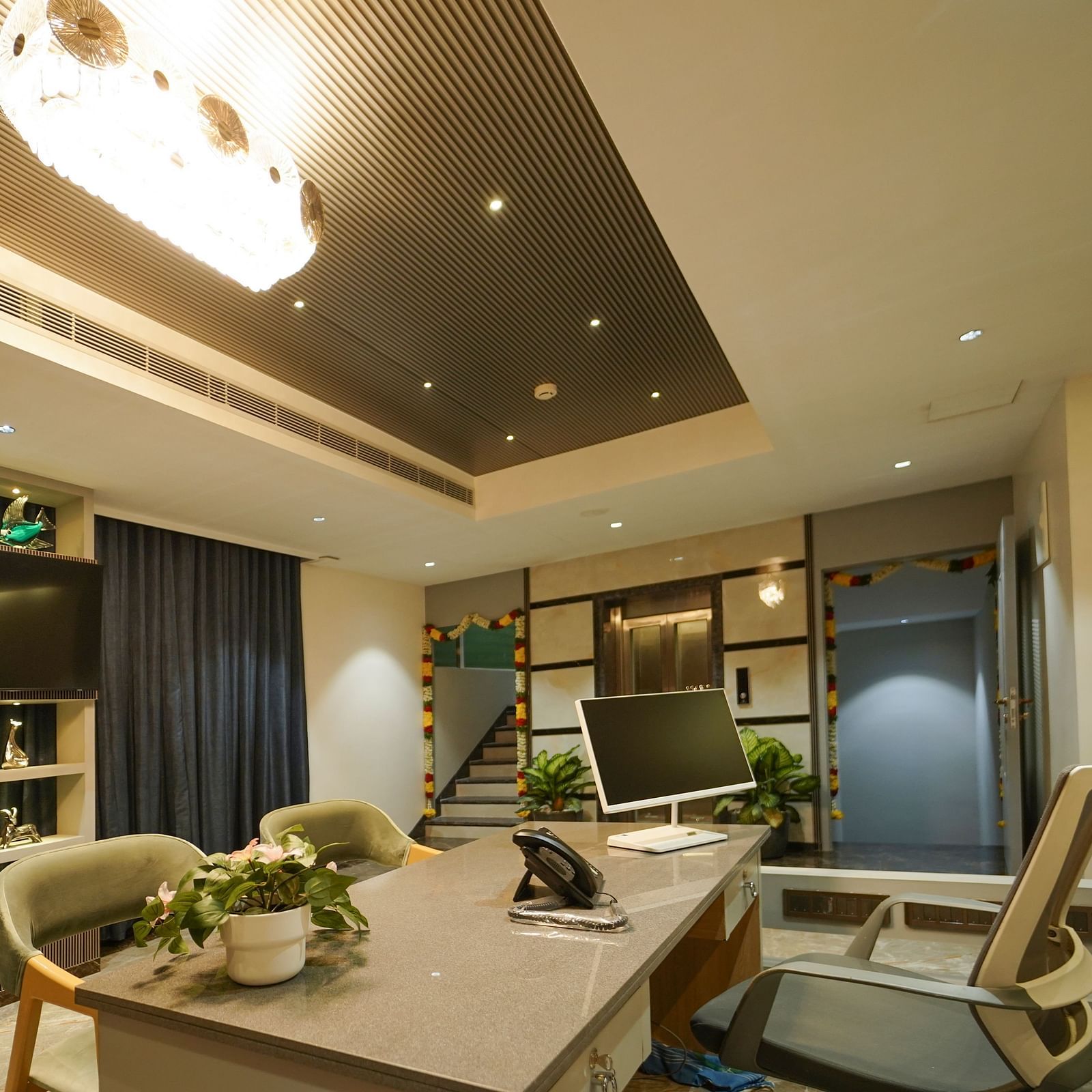 A room includes a long table with chairs, a mounted television within shelving, window coverings, and ceiling lights - Hotel Park Inn, Nellore.
