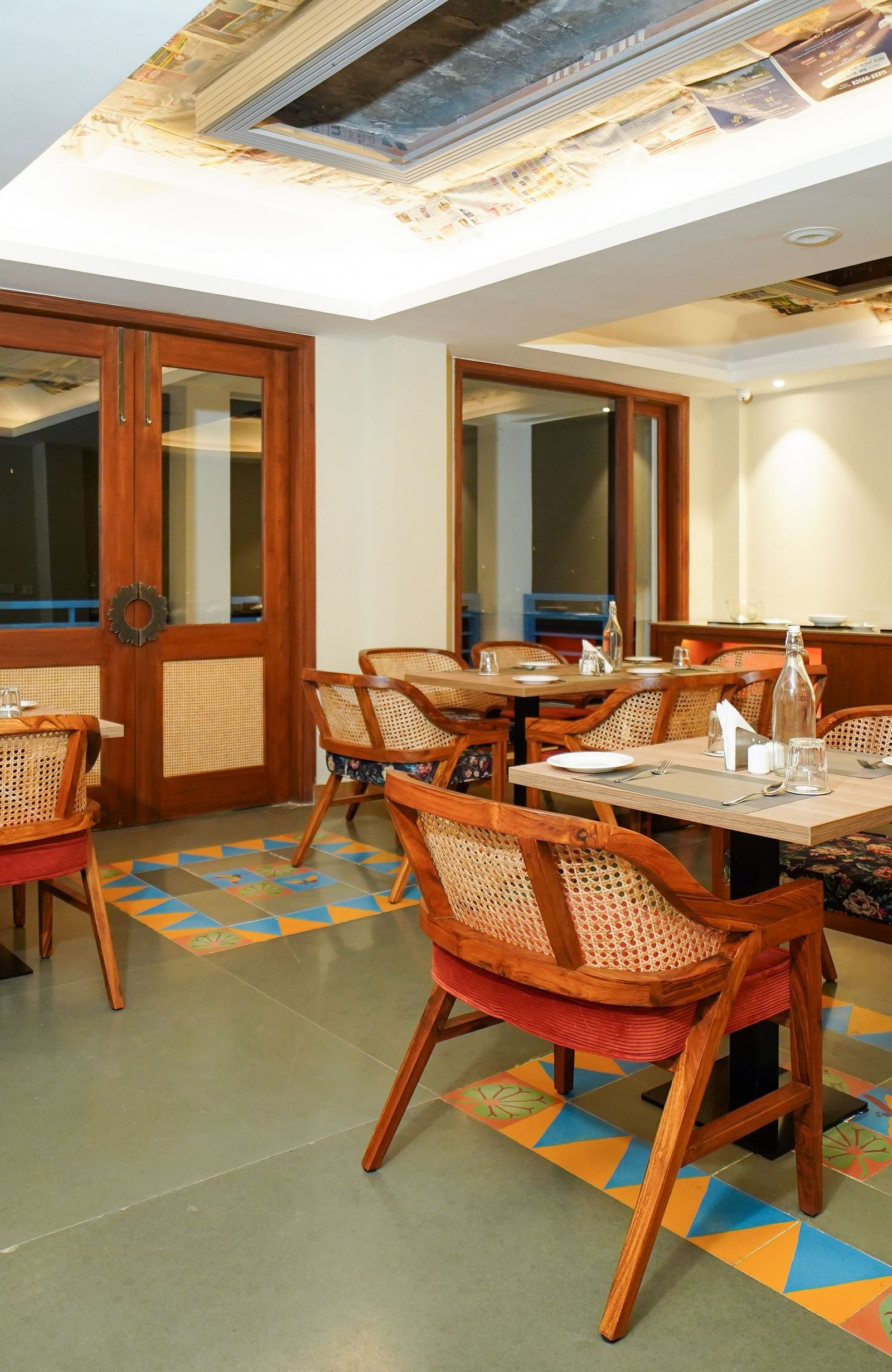 A dining area with multiple tables and chairs, featuring wooden accents and a patterned ceiling | Sukama Resort & Spa, Nainital