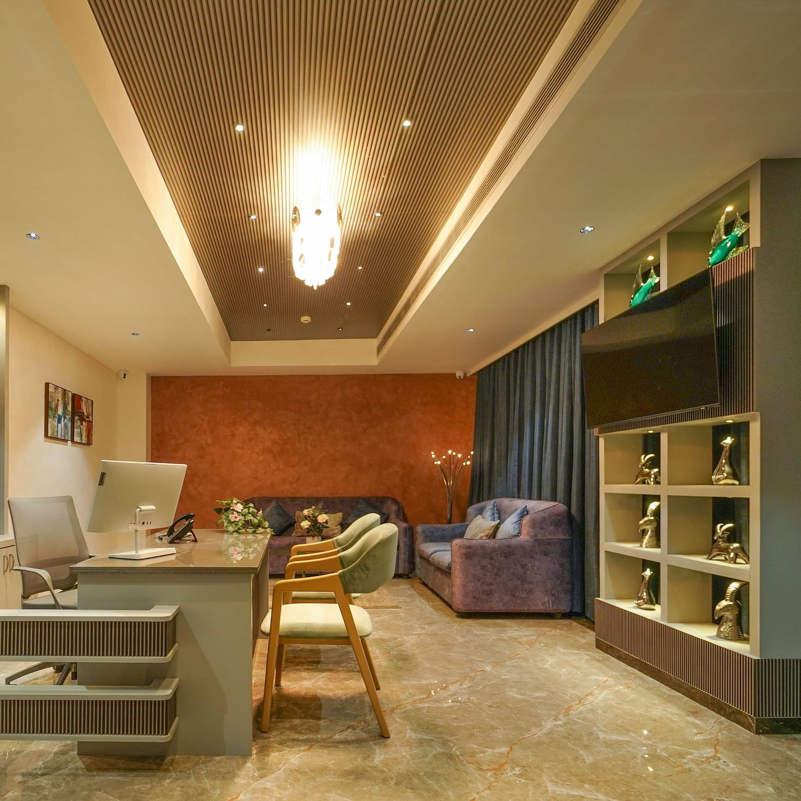 A room features a desk area with a computer, seating including a sofa and chairs, shelving with a television, and window coverings - Hotel Park Inn, Nellore.