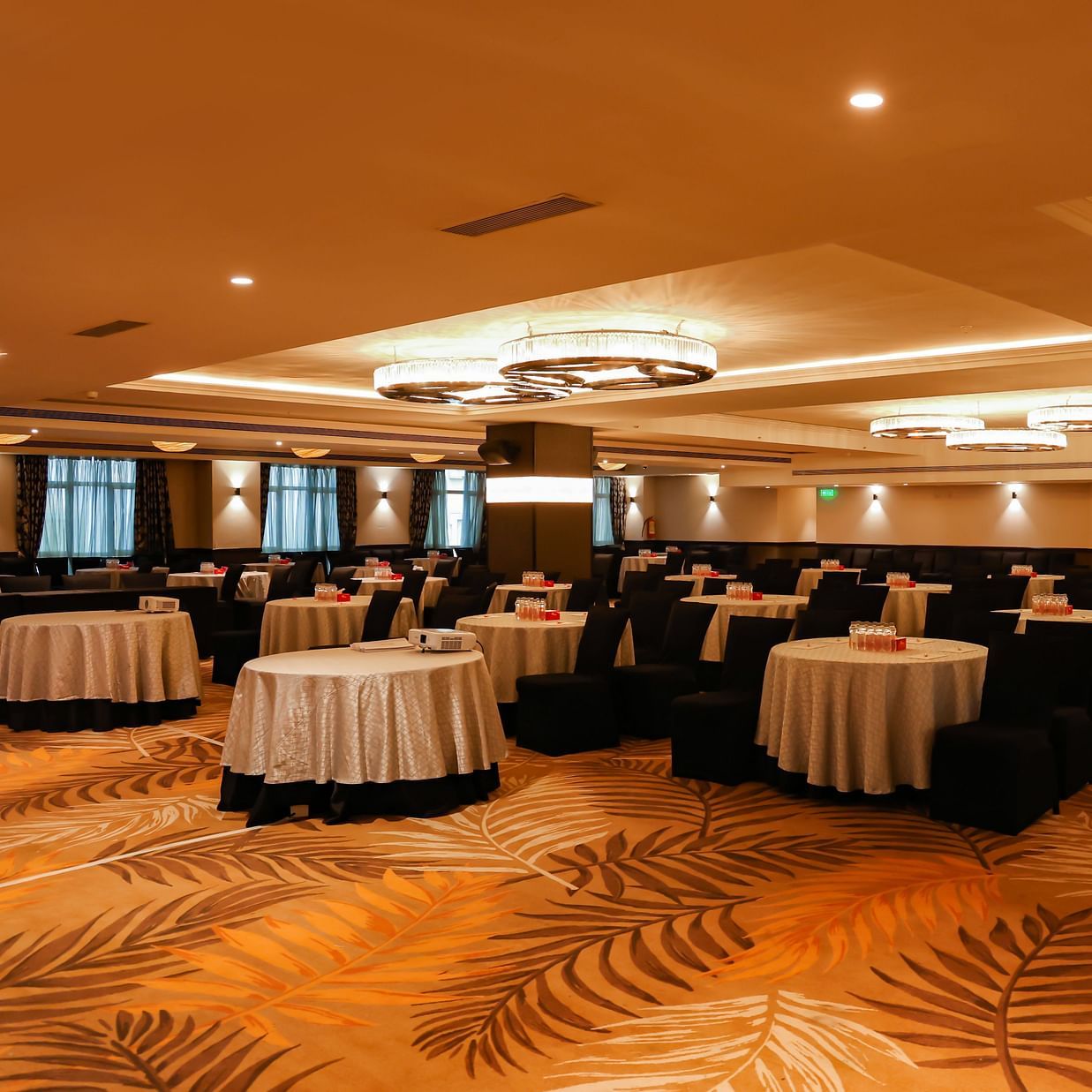 Solitaire Hall at The Beatle Hotel, Powai, arranged for a conference with round tables and a warm interior.
