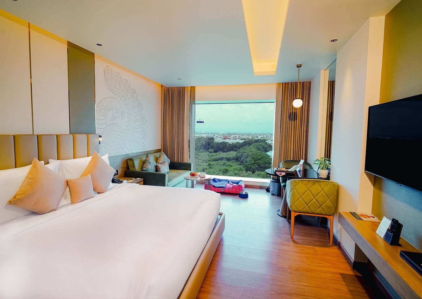 A bright and airy hotel room featuring a king size bed, sleek furnishings, with a panoramic city and greenery view - Grand Madurai by GRT Hotels