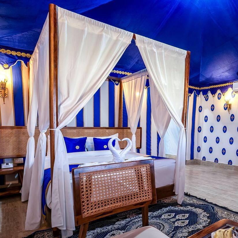 Decorated tent at Buena Vista Luxury Garden Spa Resort with a four-poster bed, blue and white striped walls, and comfortable seating.