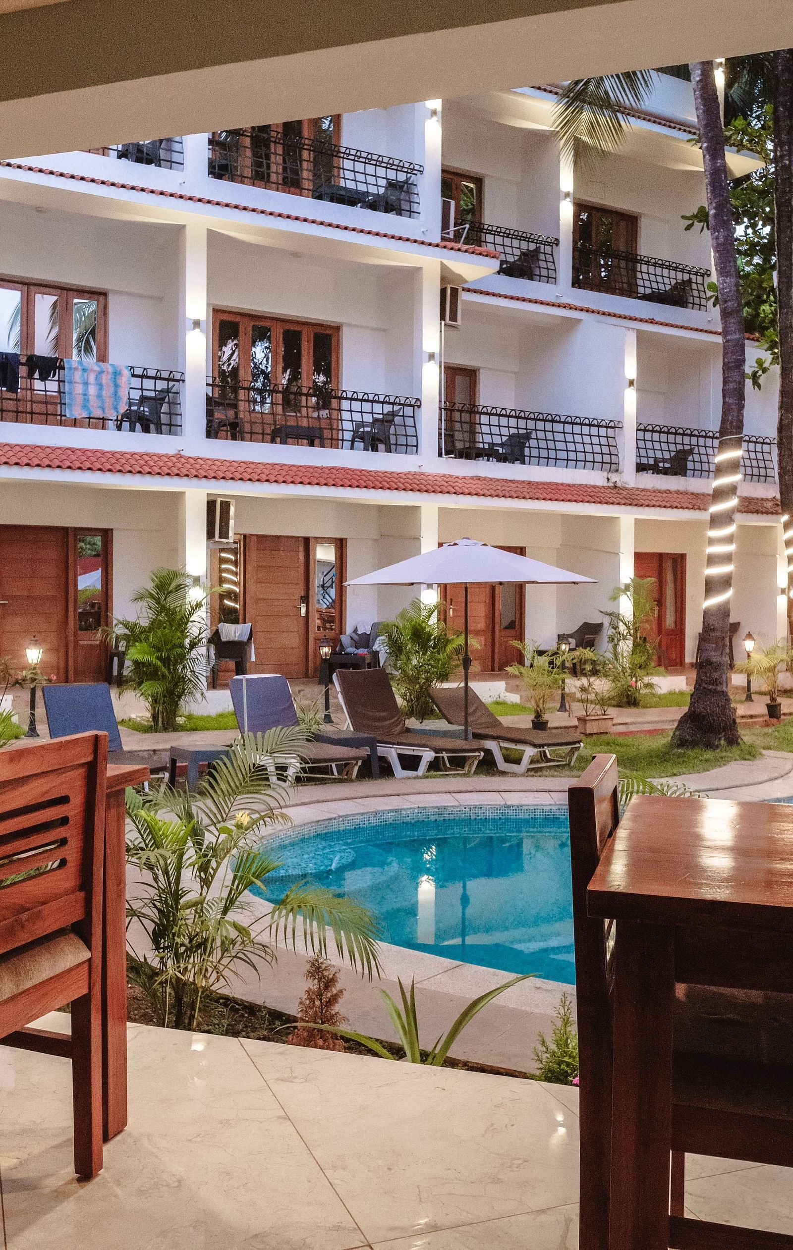 An inviting poolside dining area with wooden tables – The Verda de Miranda Resort.