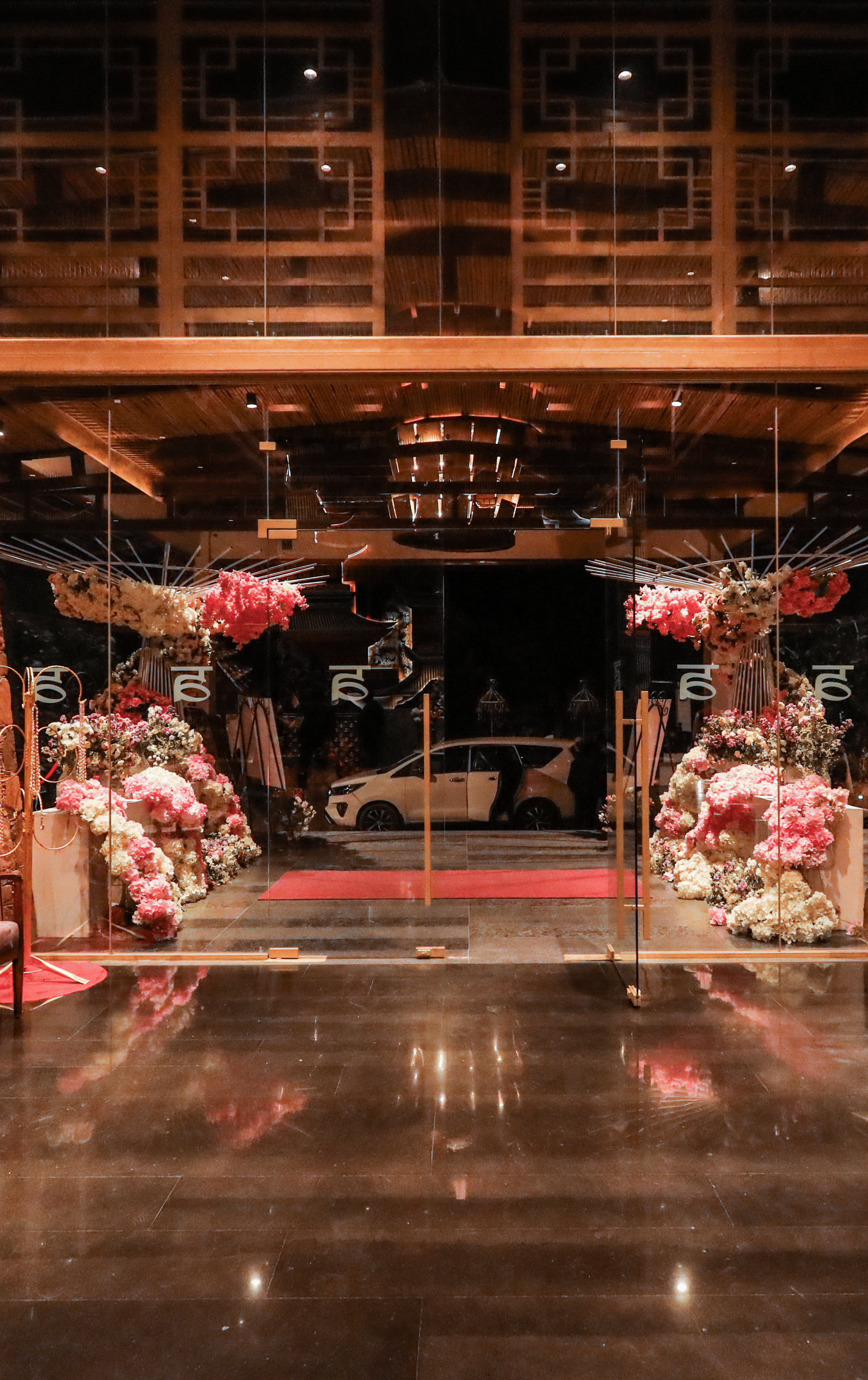 The interior entryway at Ananta Spa & Resort, Jaipur, features dark wooden floors, pink lounge chairs, and large pink floral decorations.