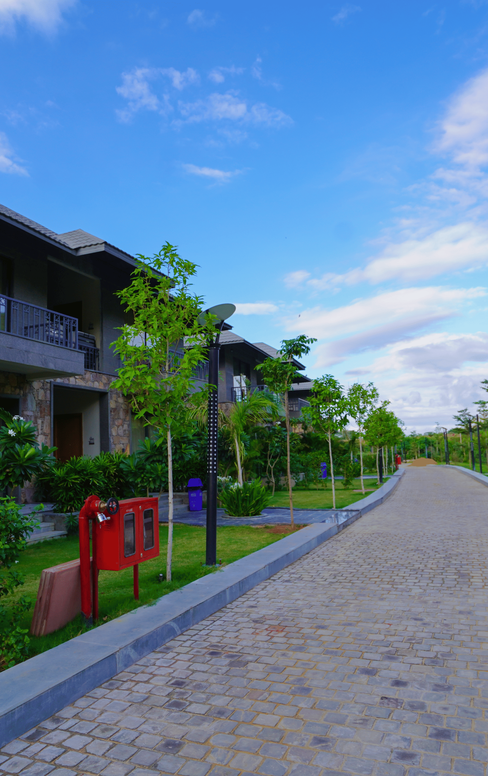 A long pathway leading to the resort villas, bordered by a green lawn and trees.