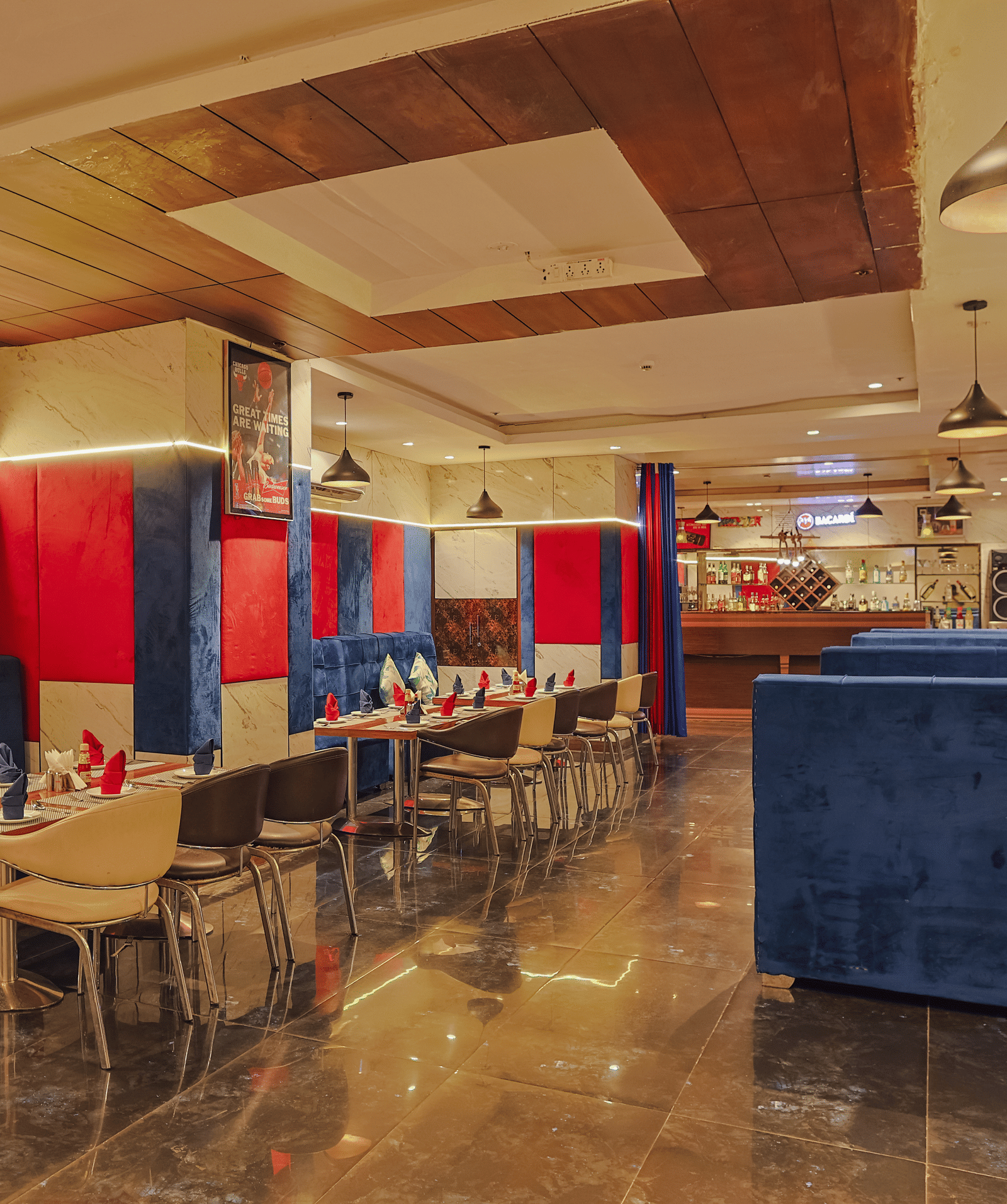 A stylish restaurant dining area with blue and red seating booths and tables - Hyphen Grand, Haridwar