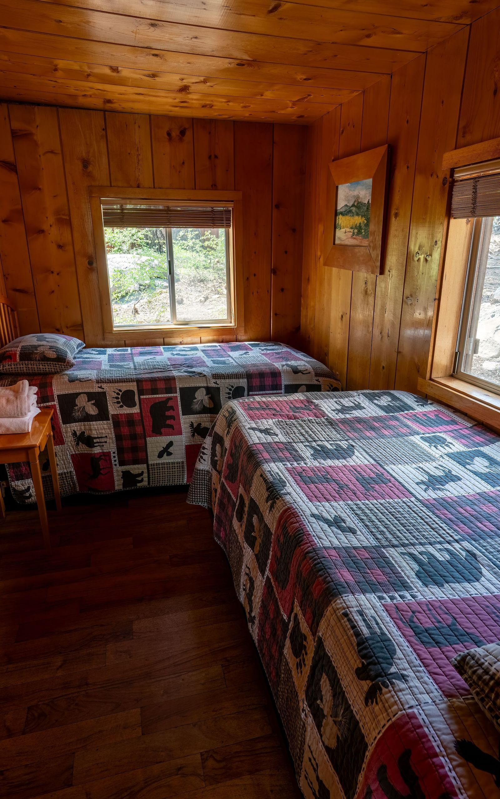 Twin beds with patterned bedding and forest views at Kit Carson Lodge.