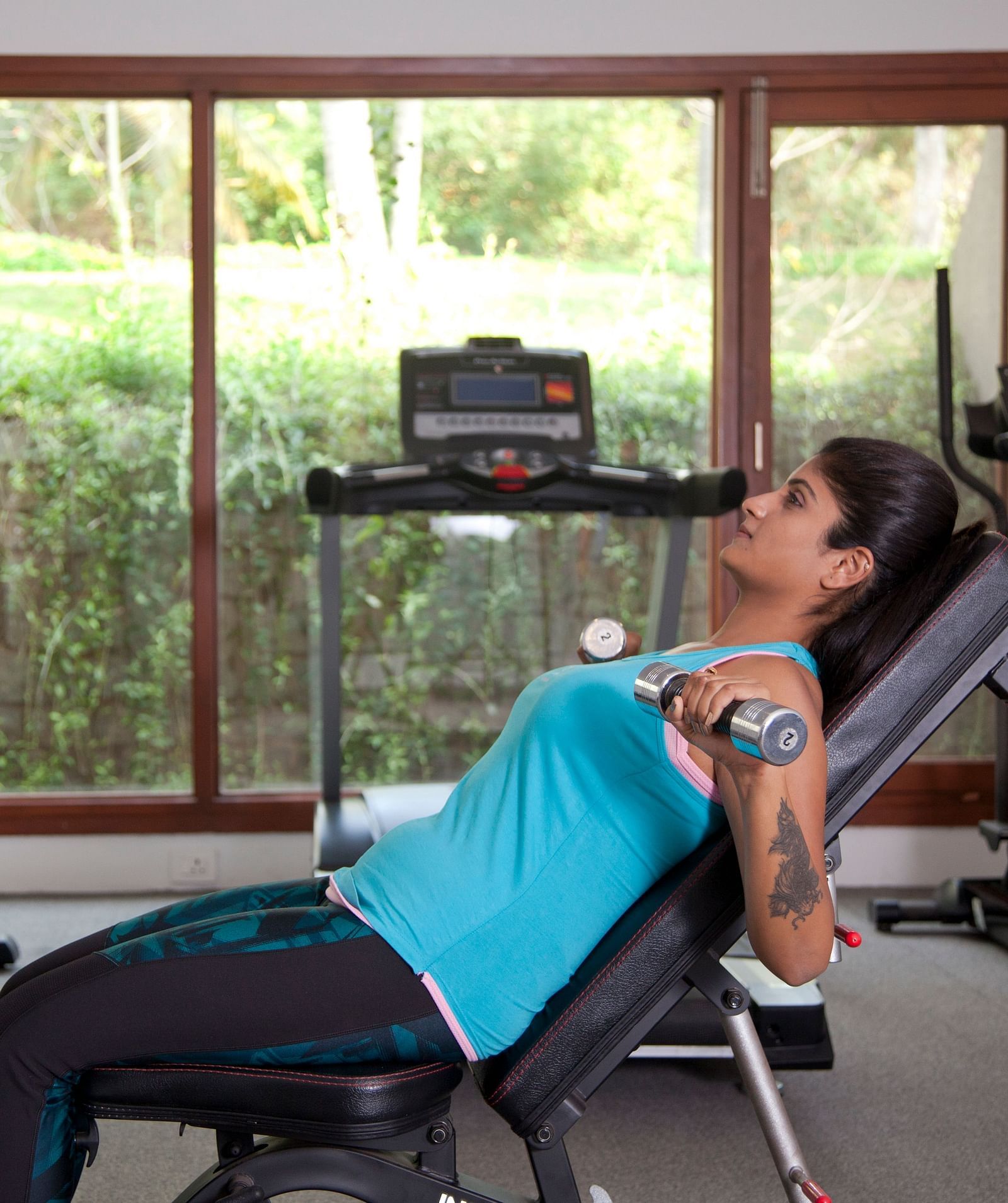 Person using exercise equipment in a room with large windows, fitness setting - Shreyas Retreat