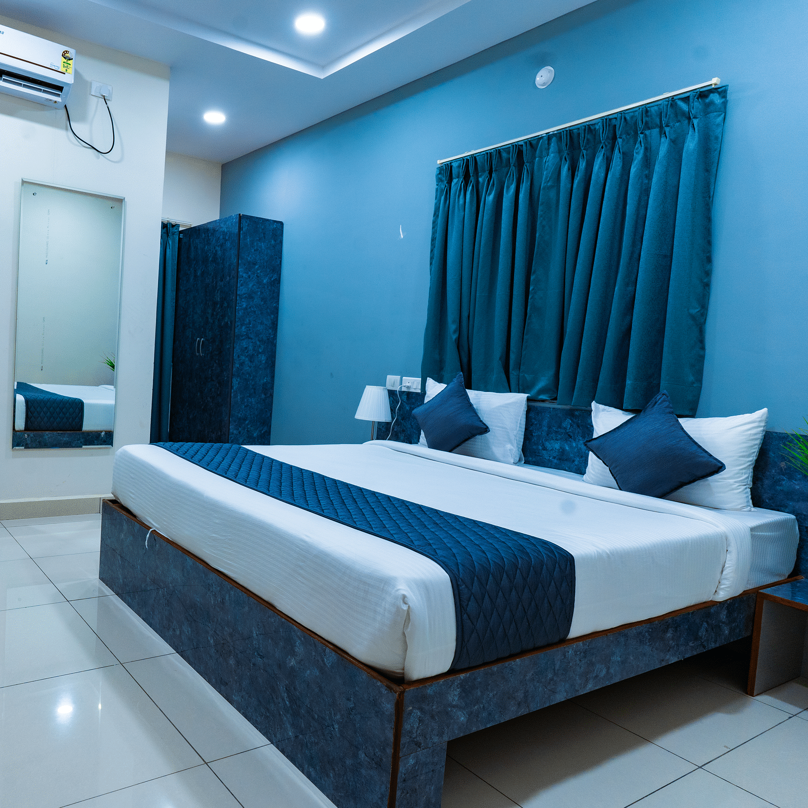 An image of a bedroom with king size bed, bedside table next to it, AC, flat TV screen, etc. - Hotel Aerotel, Hyderabad - A Unit of Comfort Hometel