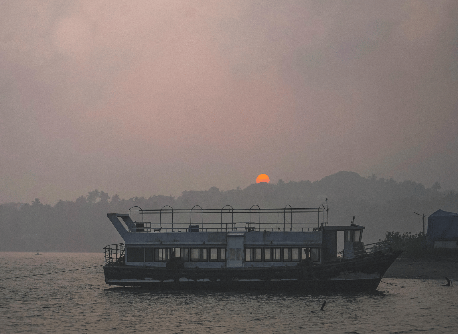 A sunset at Chapora River View Point, watched from the riverbank, featuring a boat reaching the shore.