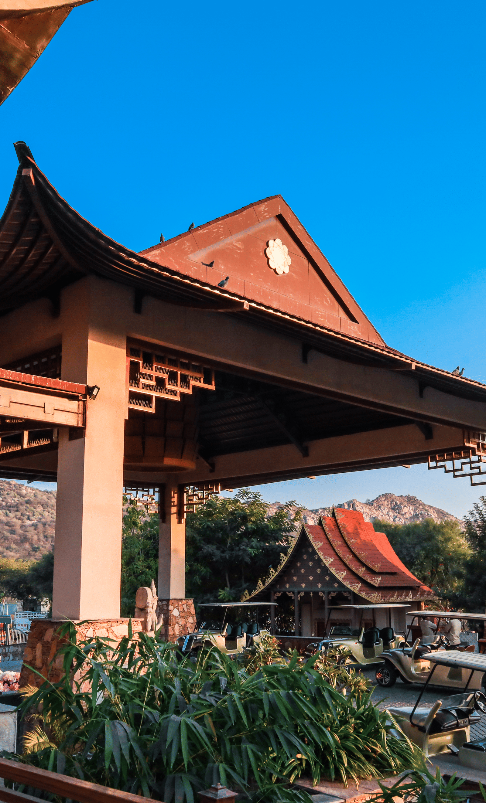 The exterior entrance of Ananta Spa & Resort, Jaipur, showcases its distinctive pagoda-style architecture against a bright blue sky.