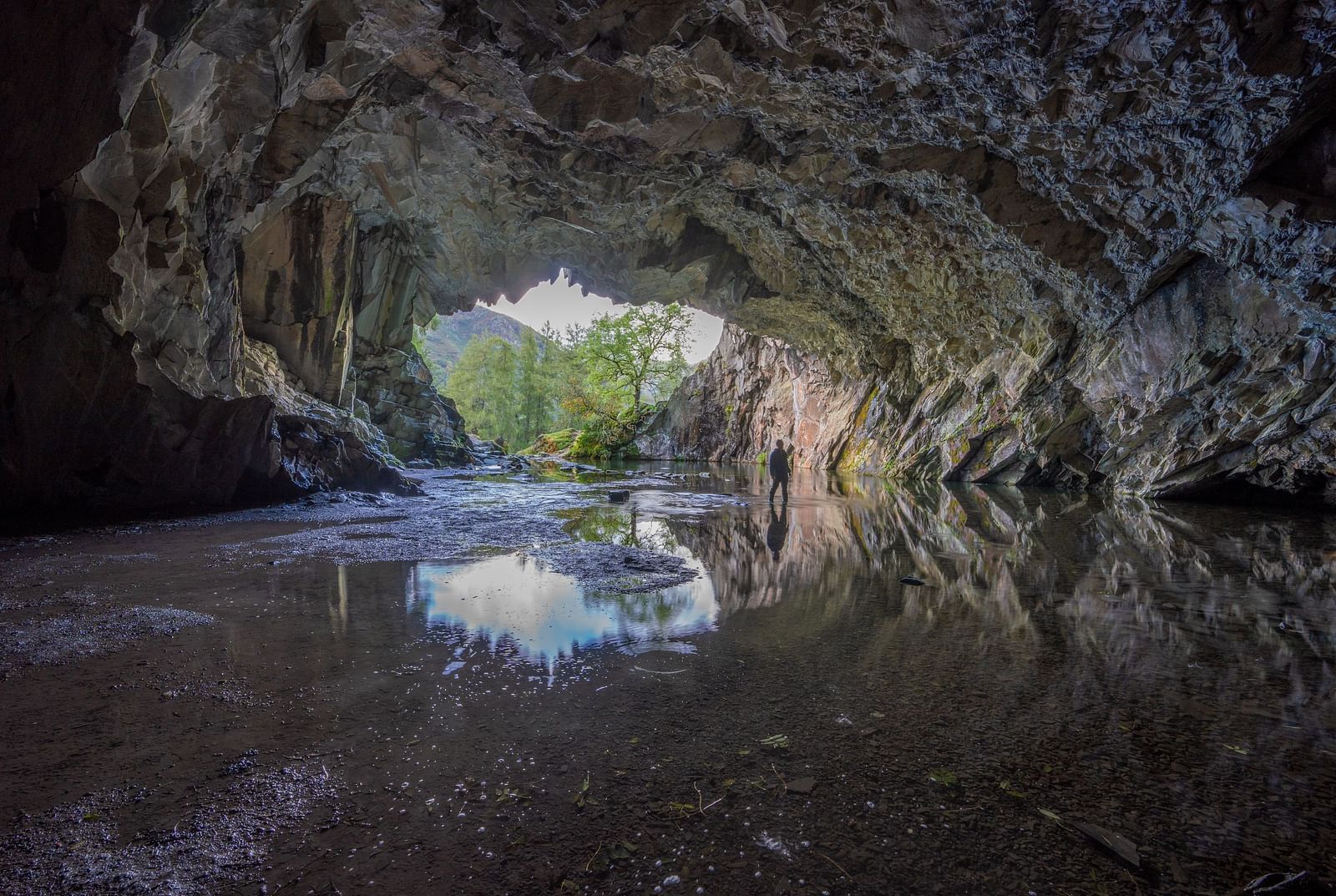 a person checking out a cave with the entrance in the background