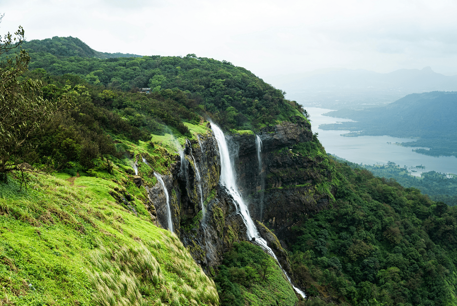 A side view of the mountains, featuring cascading waterfalls and a sky shrouded in mist