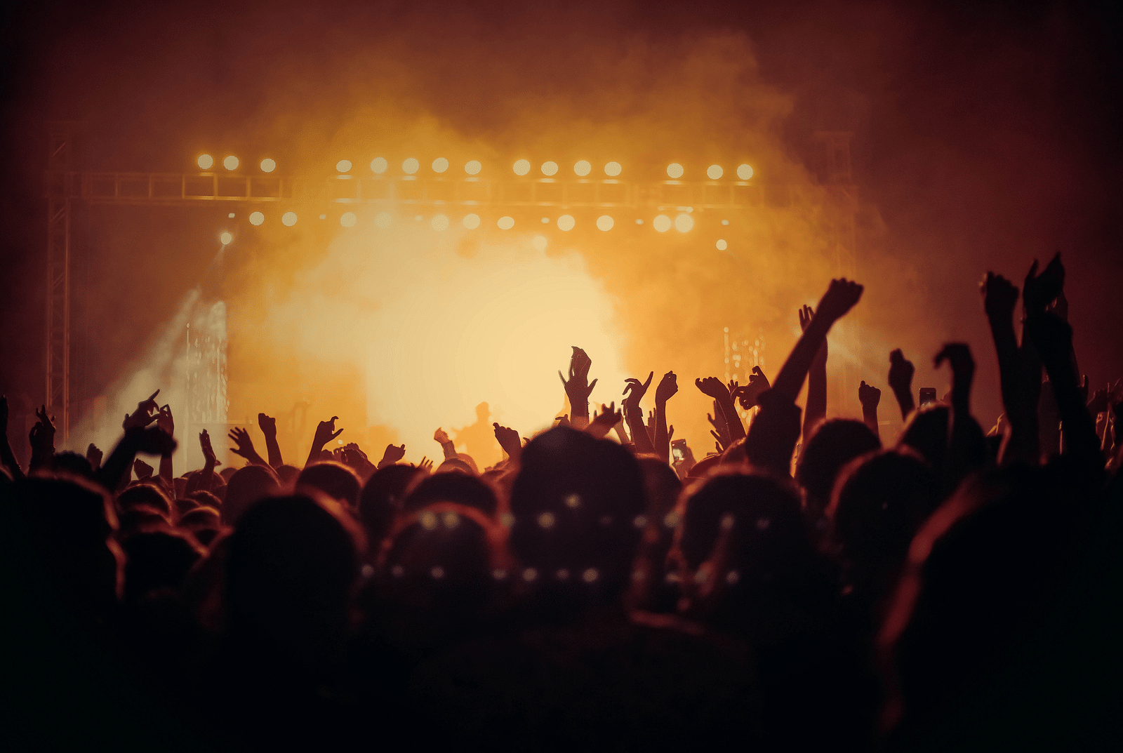 people with their hands raised in the air at a concert at night