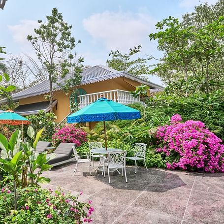 The exterior view of Mayfair Manor, Alibag, framed by trees and plants surrounding the property