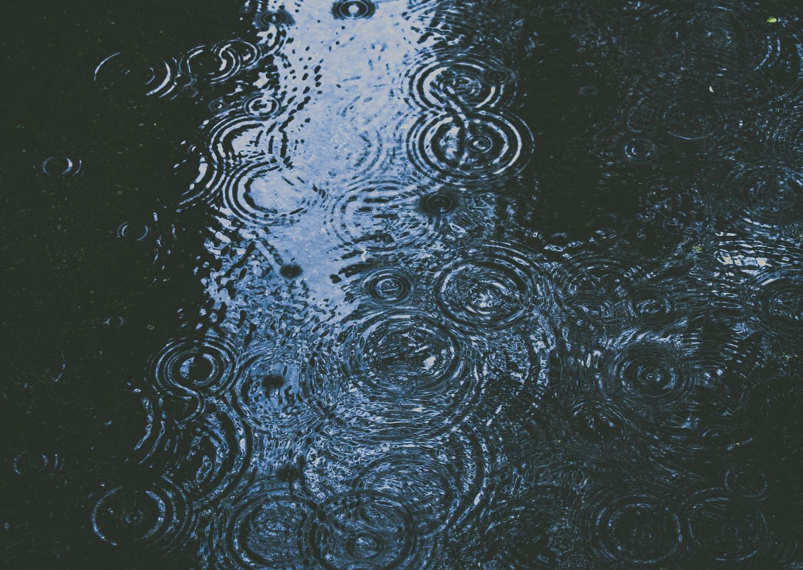 A view from above of a floor with water having water droplets falling on it.
