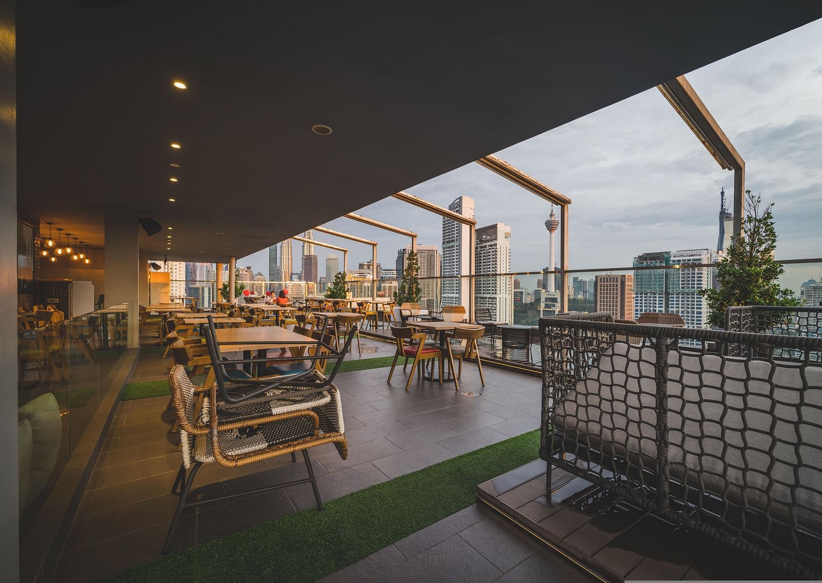 An overview of the seating arrangements inside a rooftop bar with views of a city skyline.
