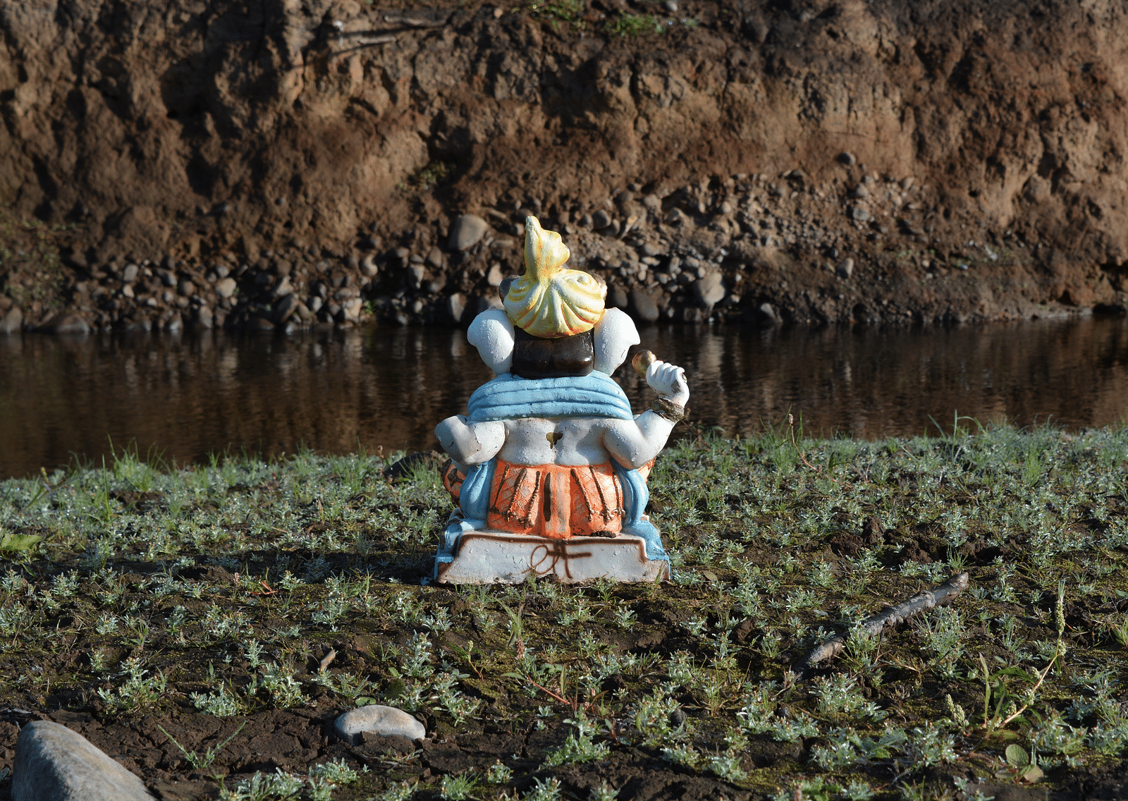 An overview of the hindu deity Ganesh's Idol in front of a waterbody.