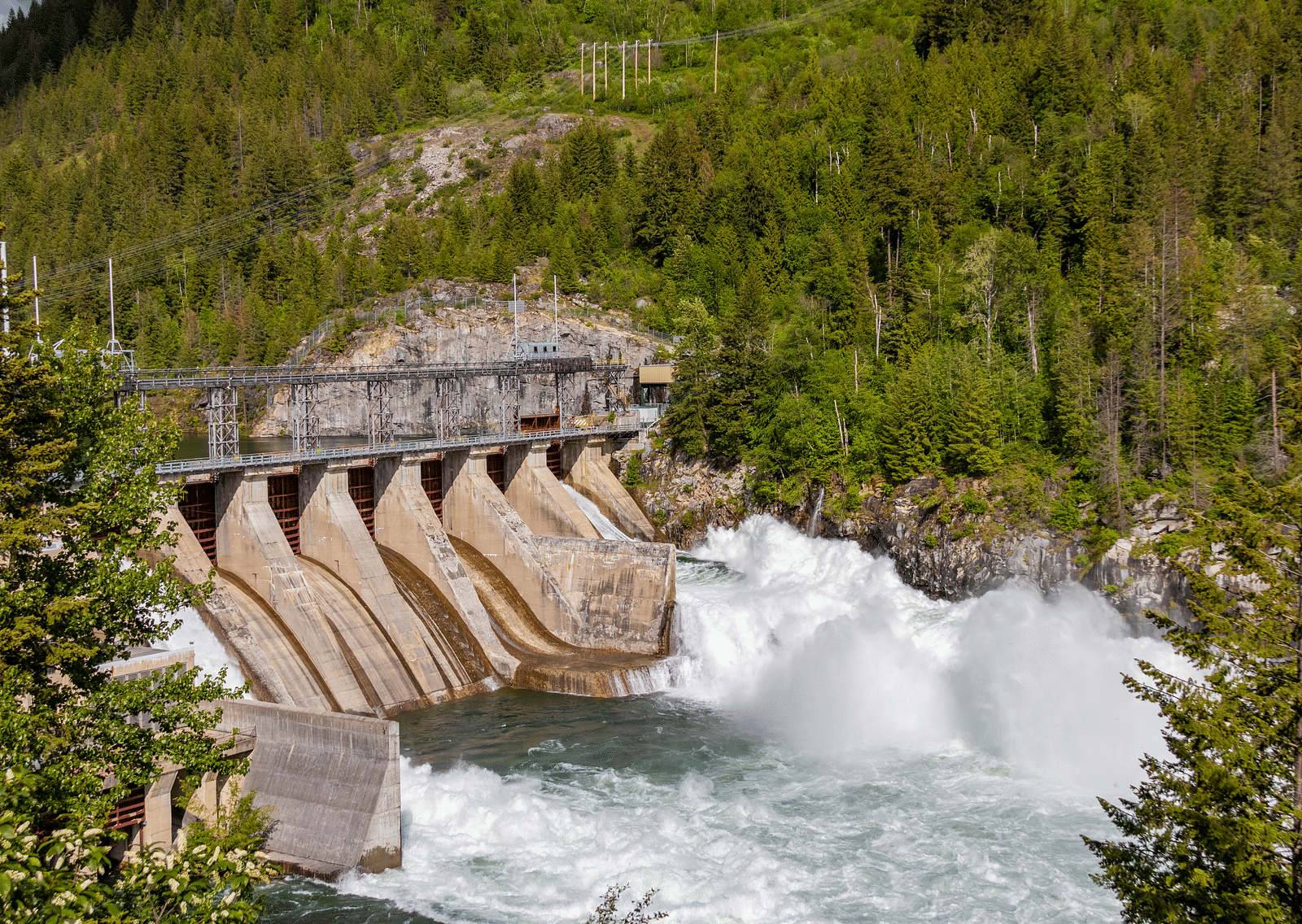 An overview of a dam with water gushing down to a waterbody. 