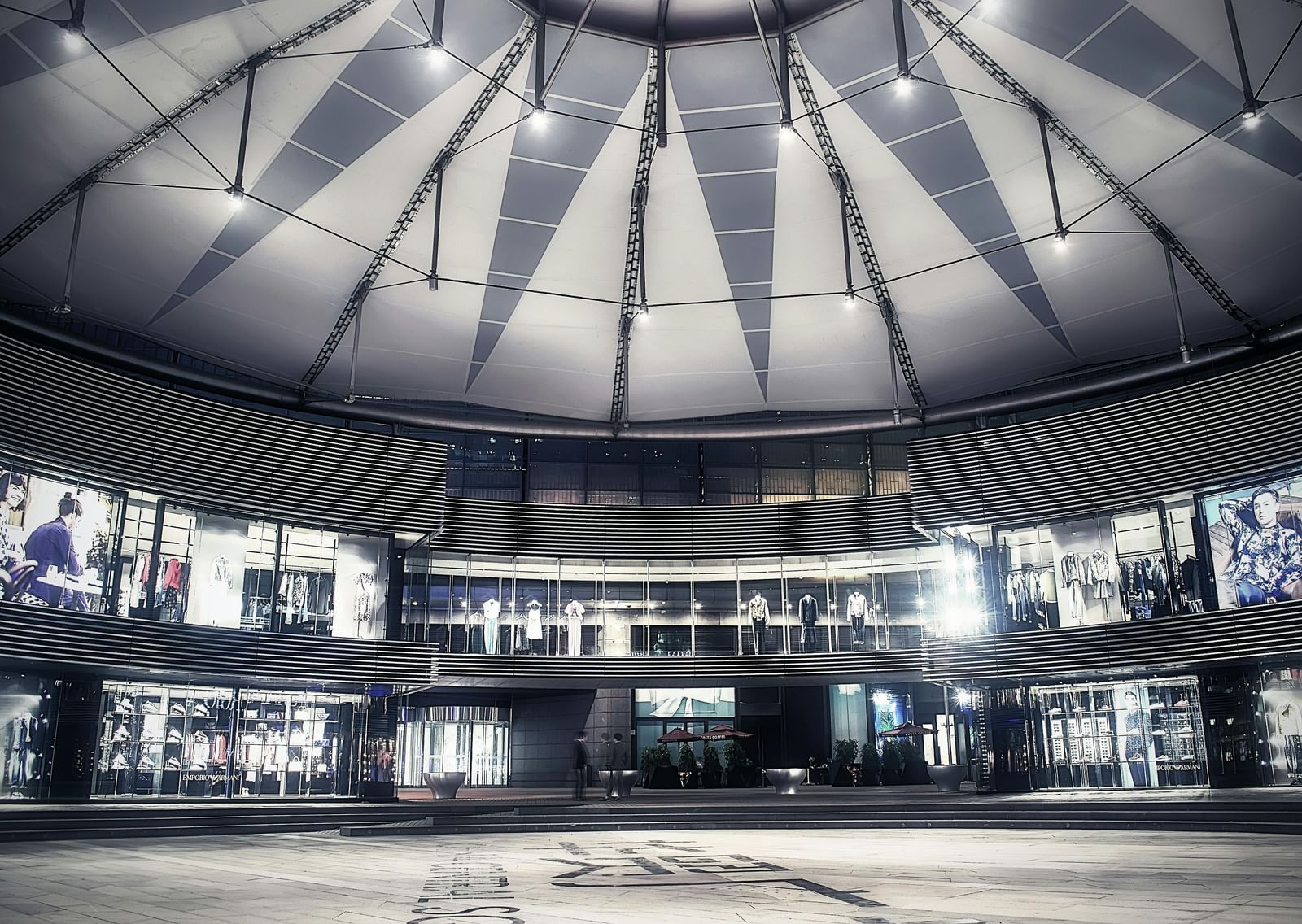 A striking modern mall interior with a domed glass ceiling, illuminated storefronts, and a sleek, spacious central walkway.