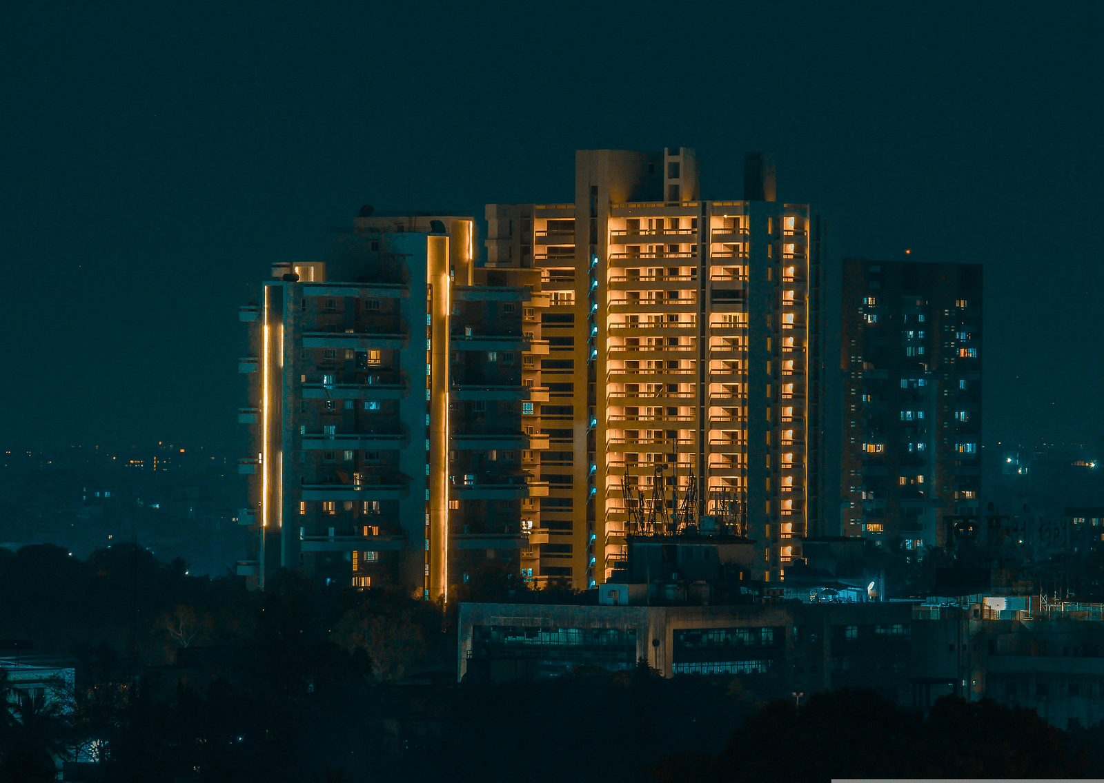 An overview of a sky rise building in Pune with the lights on in the night.