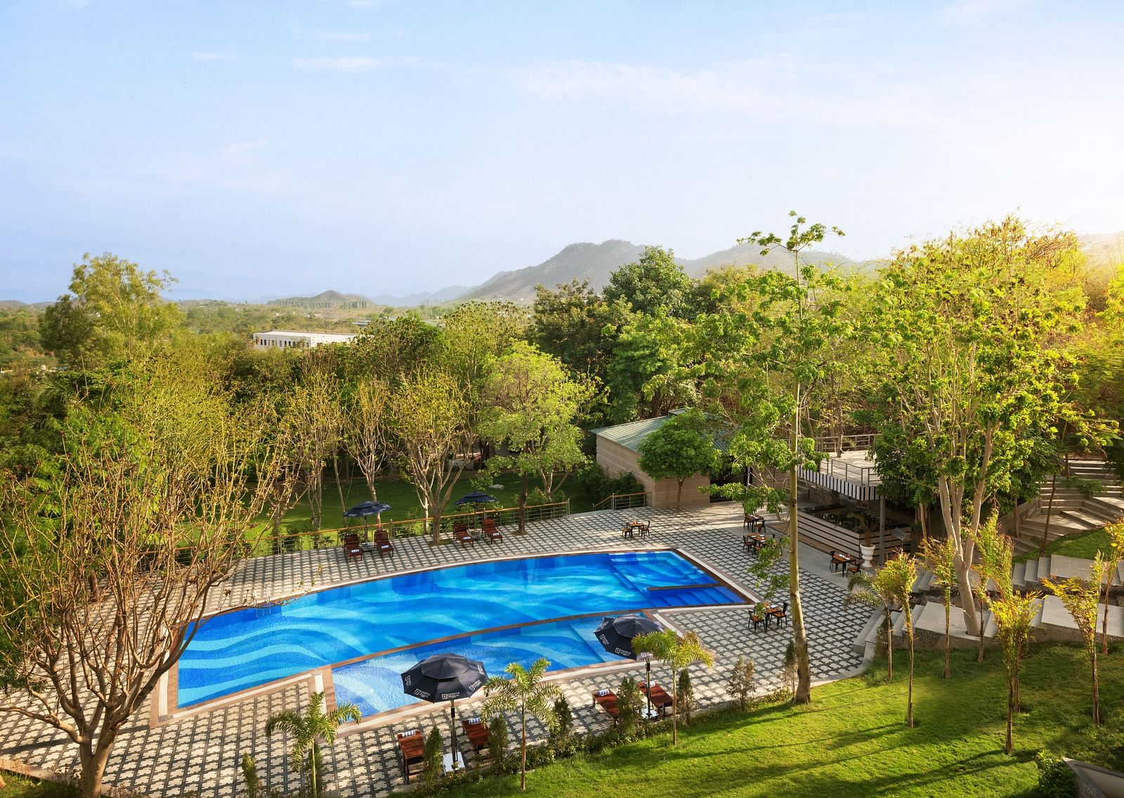 A far out view of the swimming pool surrounded by trees - Essentia Luxury Resort & Spa, Udaipur