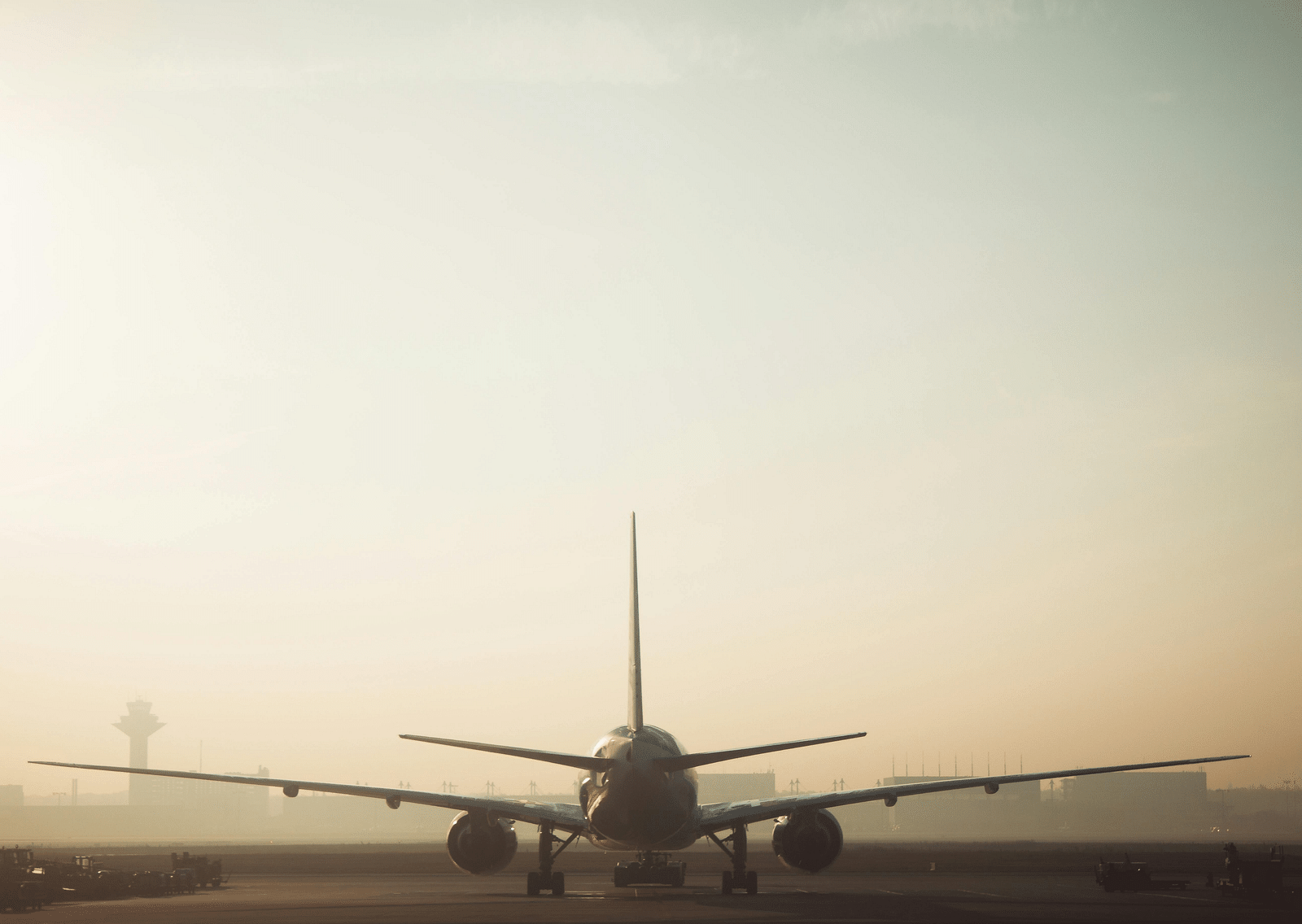 Back angle of an airplane on a runway with the morning sky in the distance.