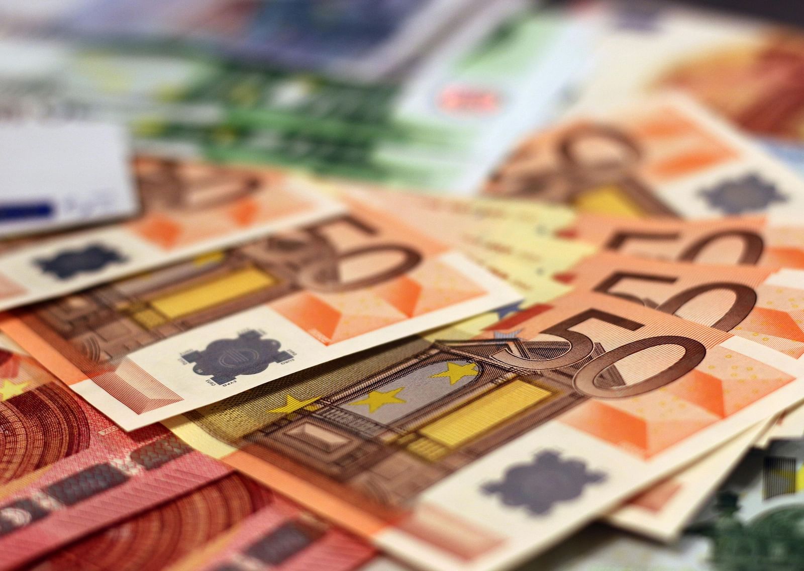 A close up shot of Many Fifty Euro bills placed on a table