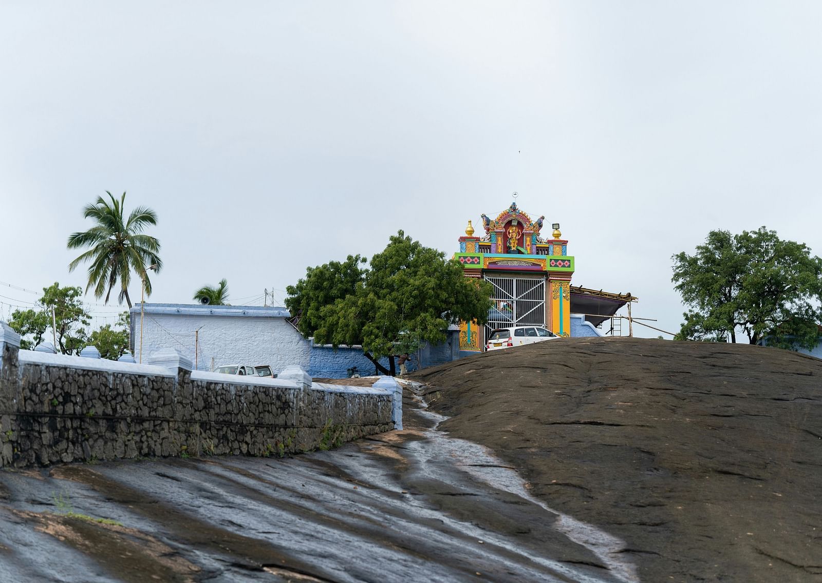 An overview of a hilltop temple with a building next to it and trees in view.