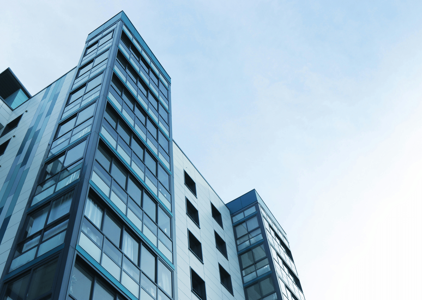 Tall modern high-rise building with glass windows and blue sky in the background