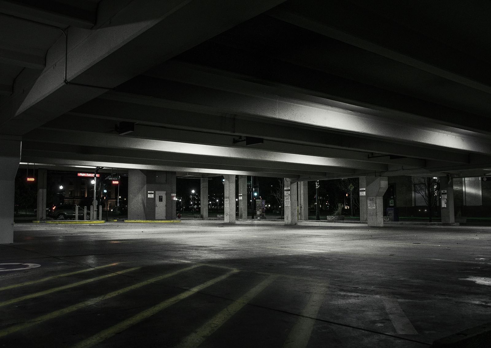 A black and white image of an empty parking lot with the lights on