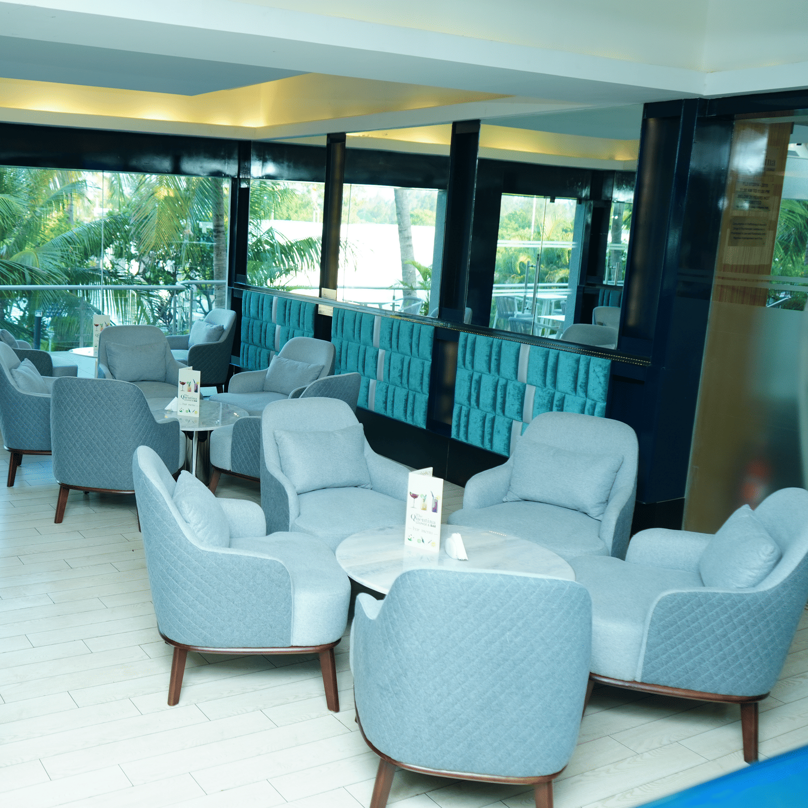 Spacious seating layout inside The Quentina Bar with multiple modern chair arrangements and bright natural light - Grande Bay Resort & Spa, Mamallapuram