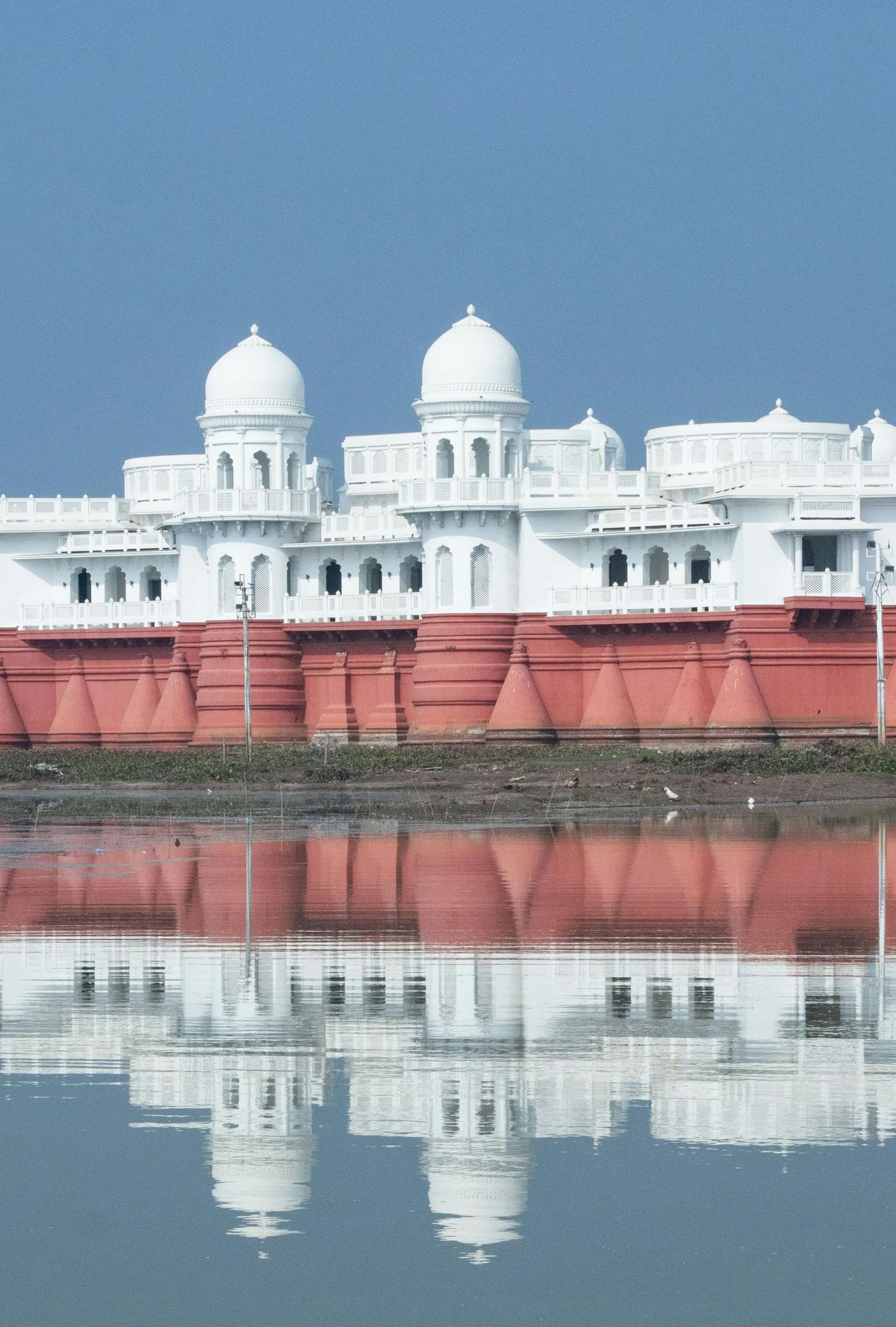 Neermahal viewed from the riverbank, its white turreted facade reflecting in the water