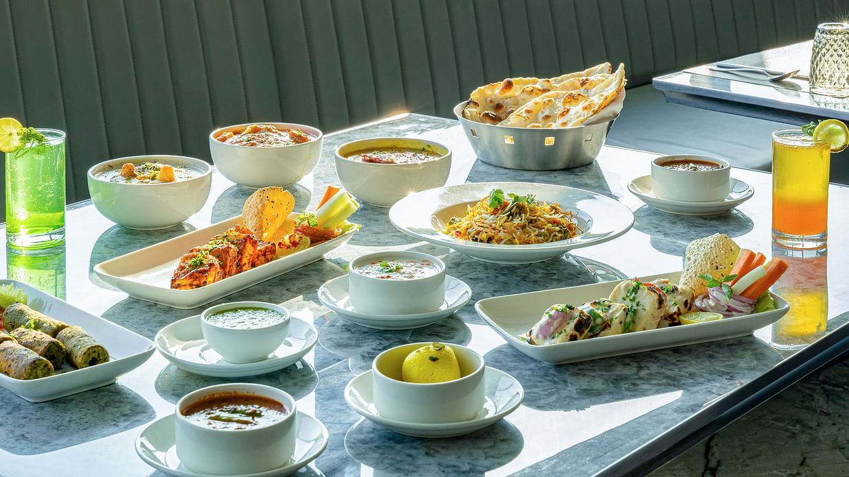 Feast spread on a marble table featuring soups, rice, curries, breads and sauces in white bowls at Clarks Inn Suites, Hyderabad