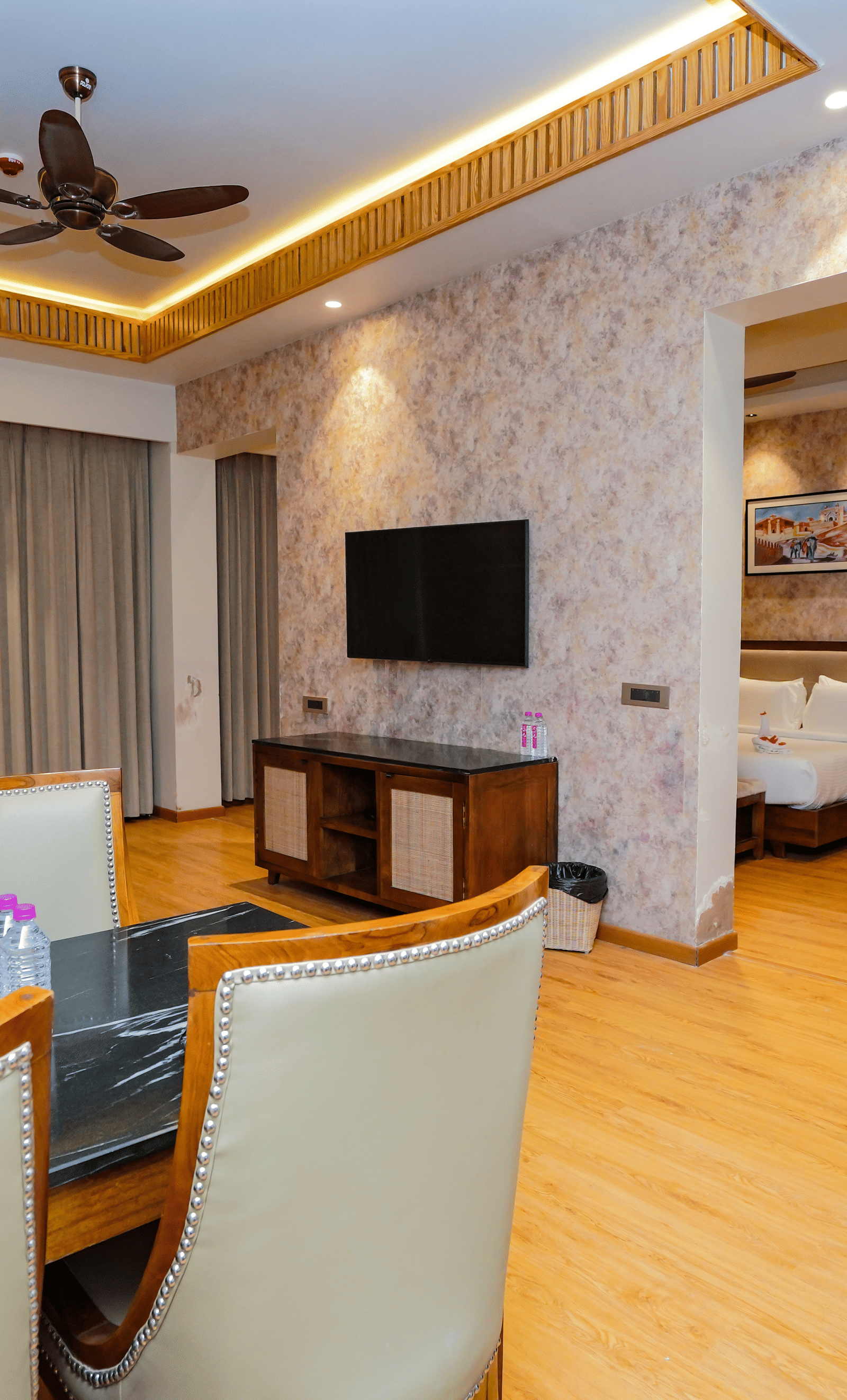 A hotel suite with a dining area and a living area, separated from the bedroom by a partition wall.