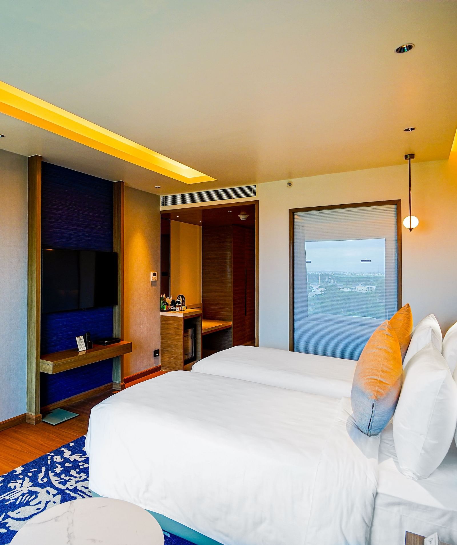 An image of Grand Club Temple View Room in Madurai with a twin bed, a work desk and hanging ceiling lamps