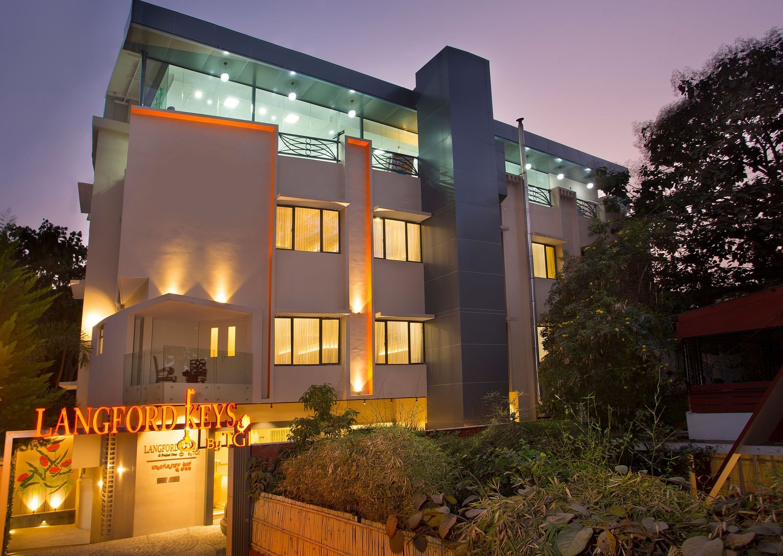 The exterior entrance of Langford Keys Hotel showing the signboard with reflective windows and modern architecture at dusk - Hotel Langford Keys by TGI, Shanti Nagar