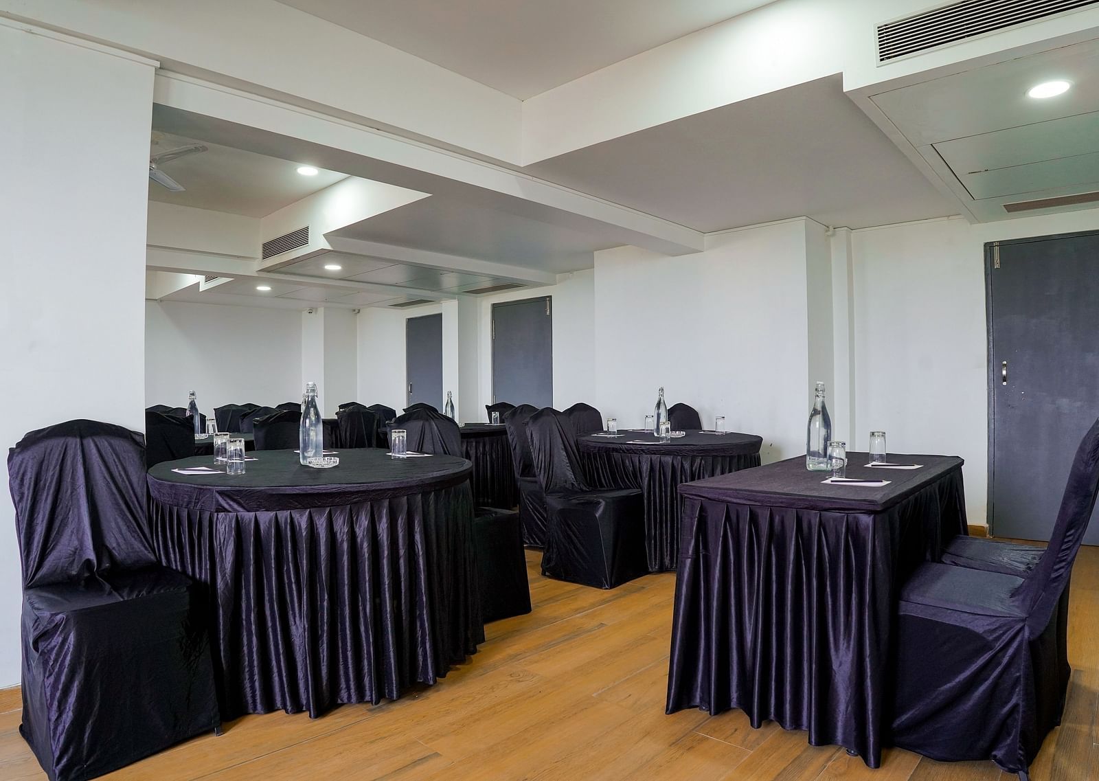 Spacious conference room with round tables and chairs covered in black - TGI Ameya Grand, Goa