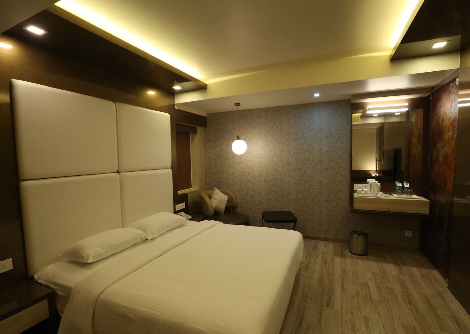 A hotel room with a king size bed under ambient lighting - TGI SPS Grand, Ram Nagar, Coimbatore