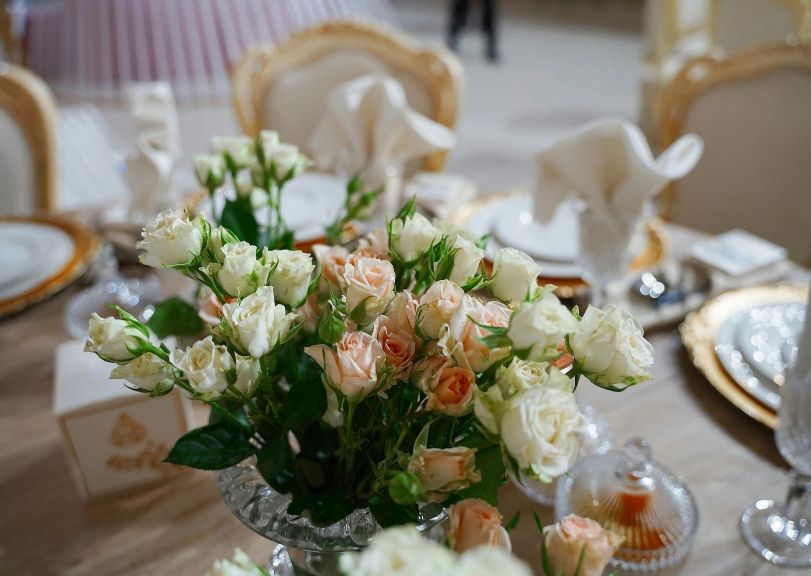 a close up image of a beautiful flower vase with a lot of white and pink roses on a dining table