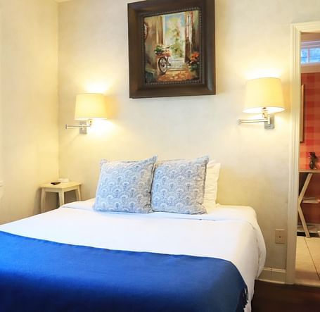 Bedroom with a blue throw, white bedding, and framed art at Hartstone Inn.