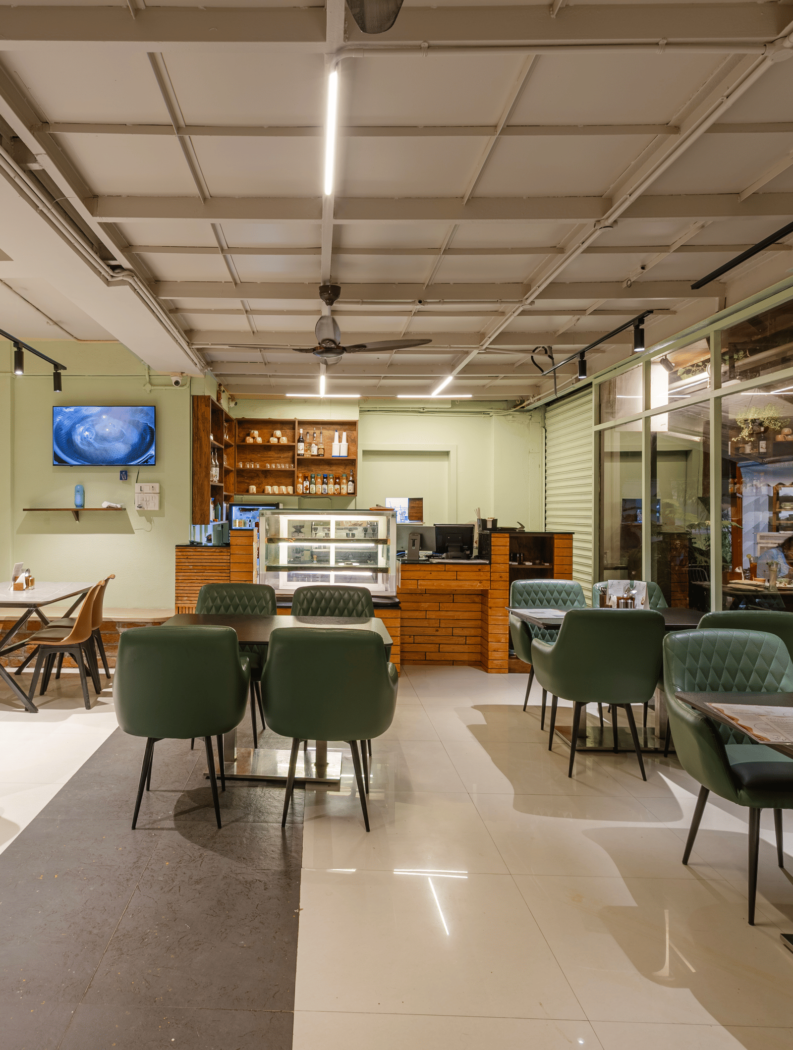 Indoor dining area of Claysutra Pottery Studio And Cafe at Kove Smart Stays that is furnished with multiple dining tables, a display case, and ample lighting.