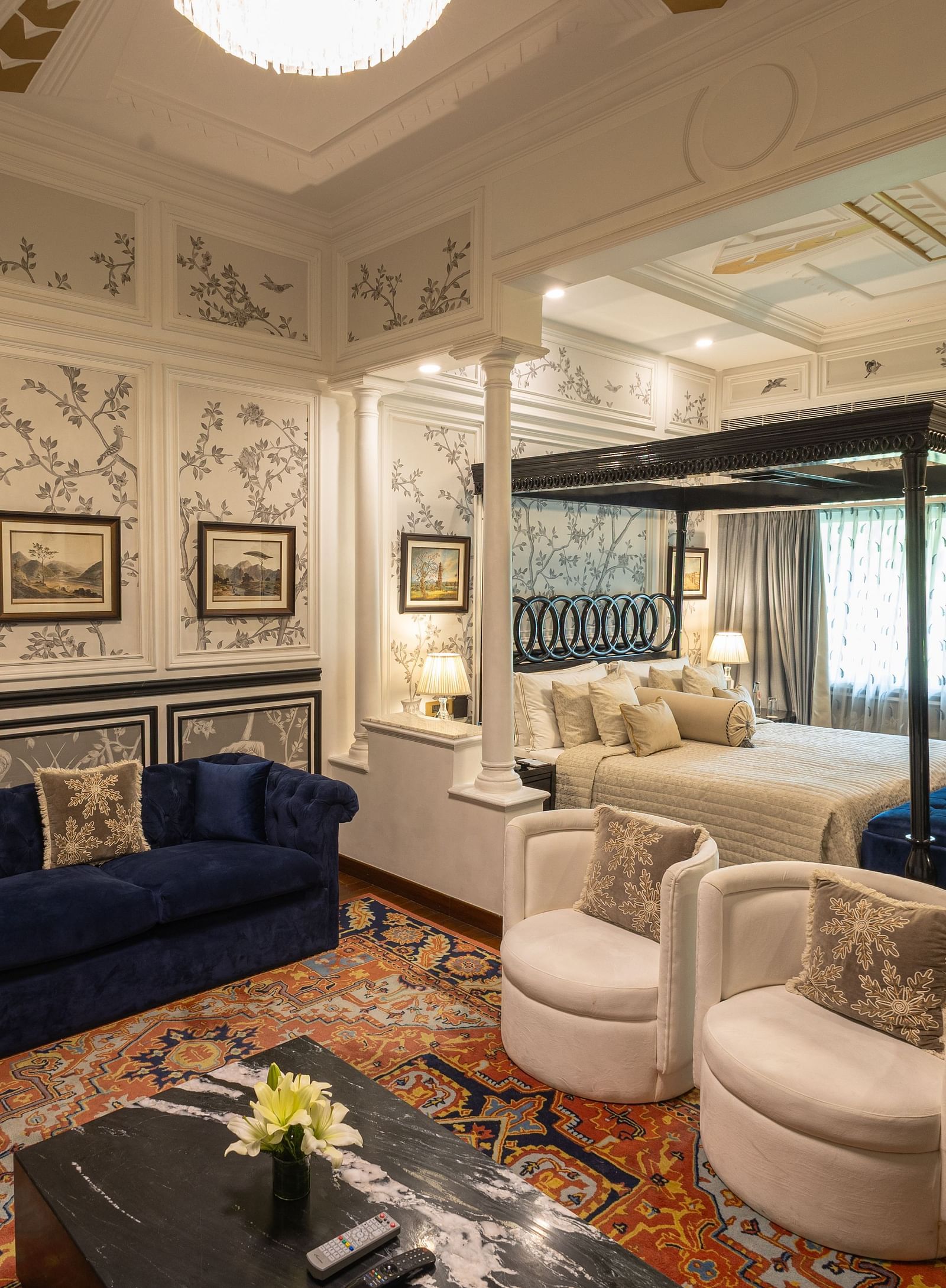 Grand Luxury Room at The Claridges New Delhi, featuring a cosy corner with a plush sofa and a chandelier hanging overhead
