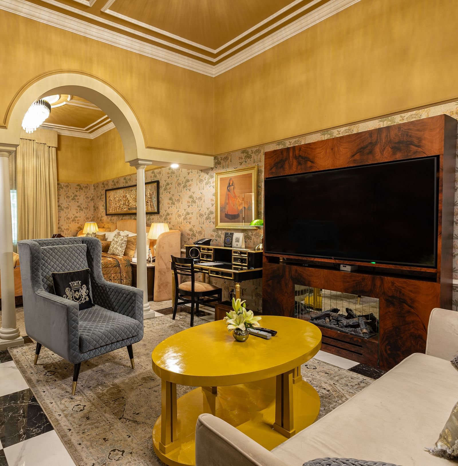 Executive Suite at The Claridges New Delhi, featuring a corner view of the room with a wall-mounted TV, cosy sofa, and a round table in front