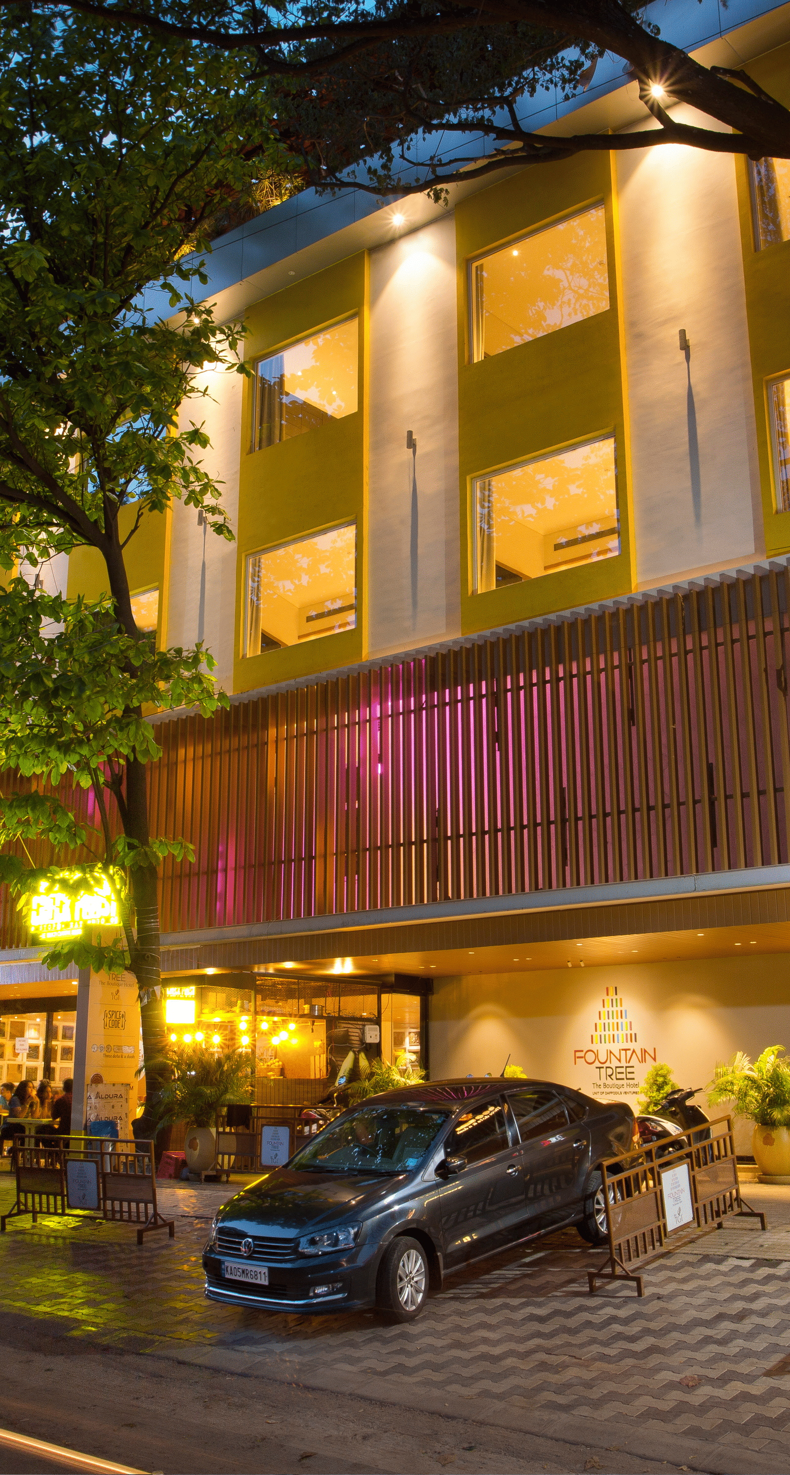 wide view of the facade of the hotel with cars parked outside the front - Hotel Fountain Tree By TGI - JP Nagar, Bangalore
